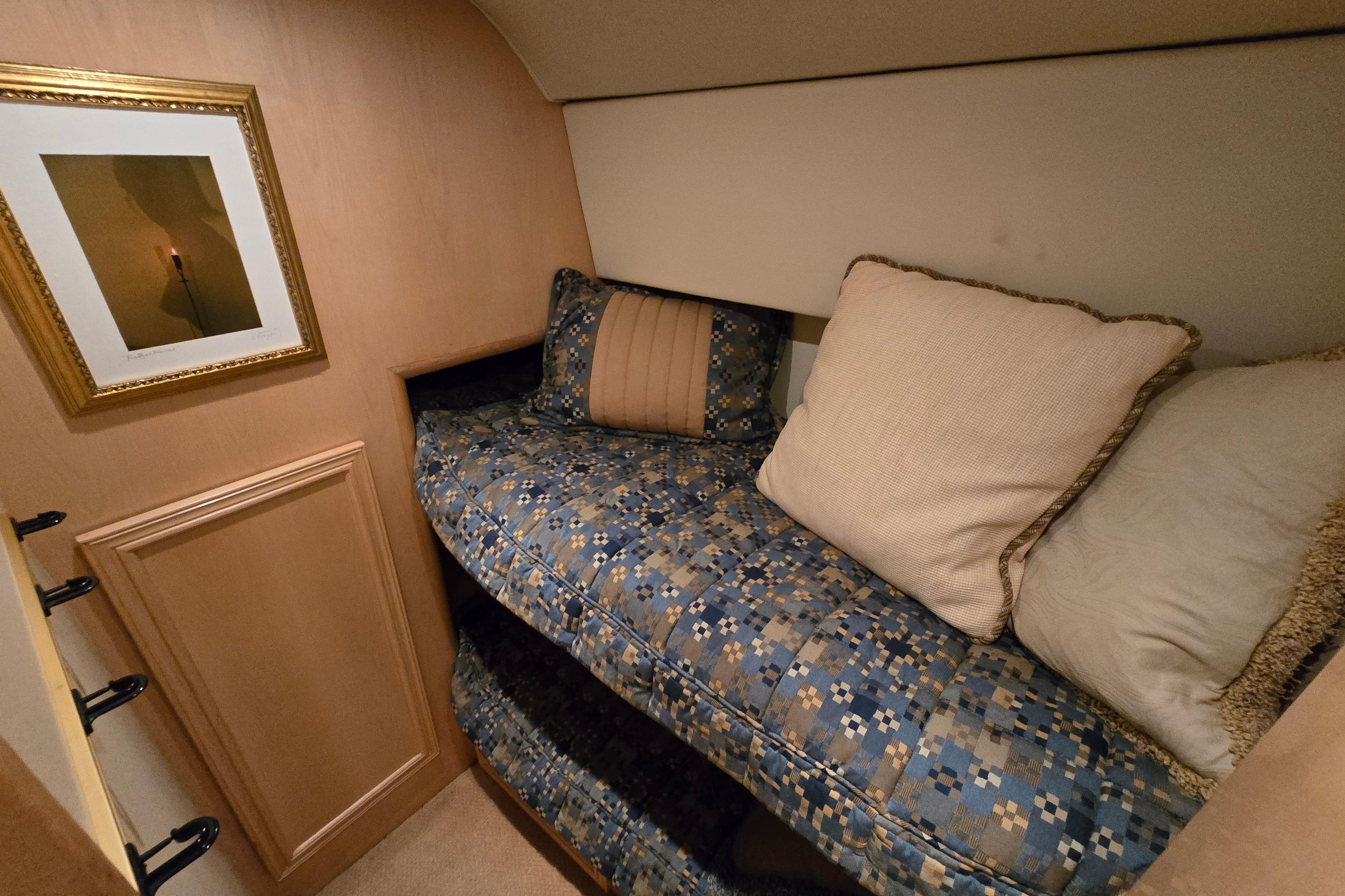 Cozy cabin interior of 2001 Cavileer 53 Convertible with patterned bedding and framed artwork.