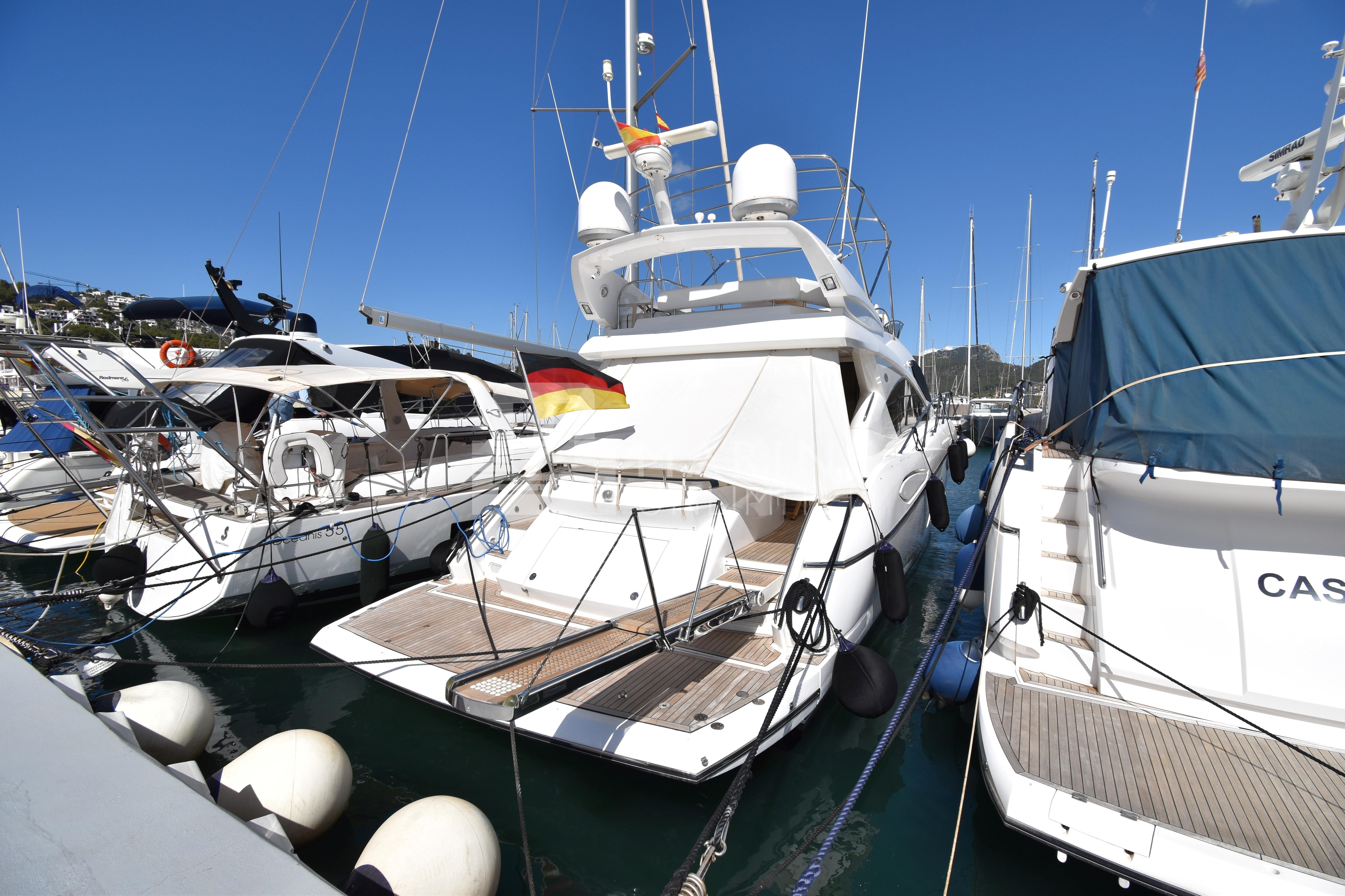Sunseeker Manhattan 52 yacht, 2010 model, docked in a marina under clear blue skies.