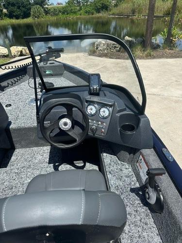 2025 Bass Tracker PGV16WT boat interior with steering wheel and dashboard by a lake.