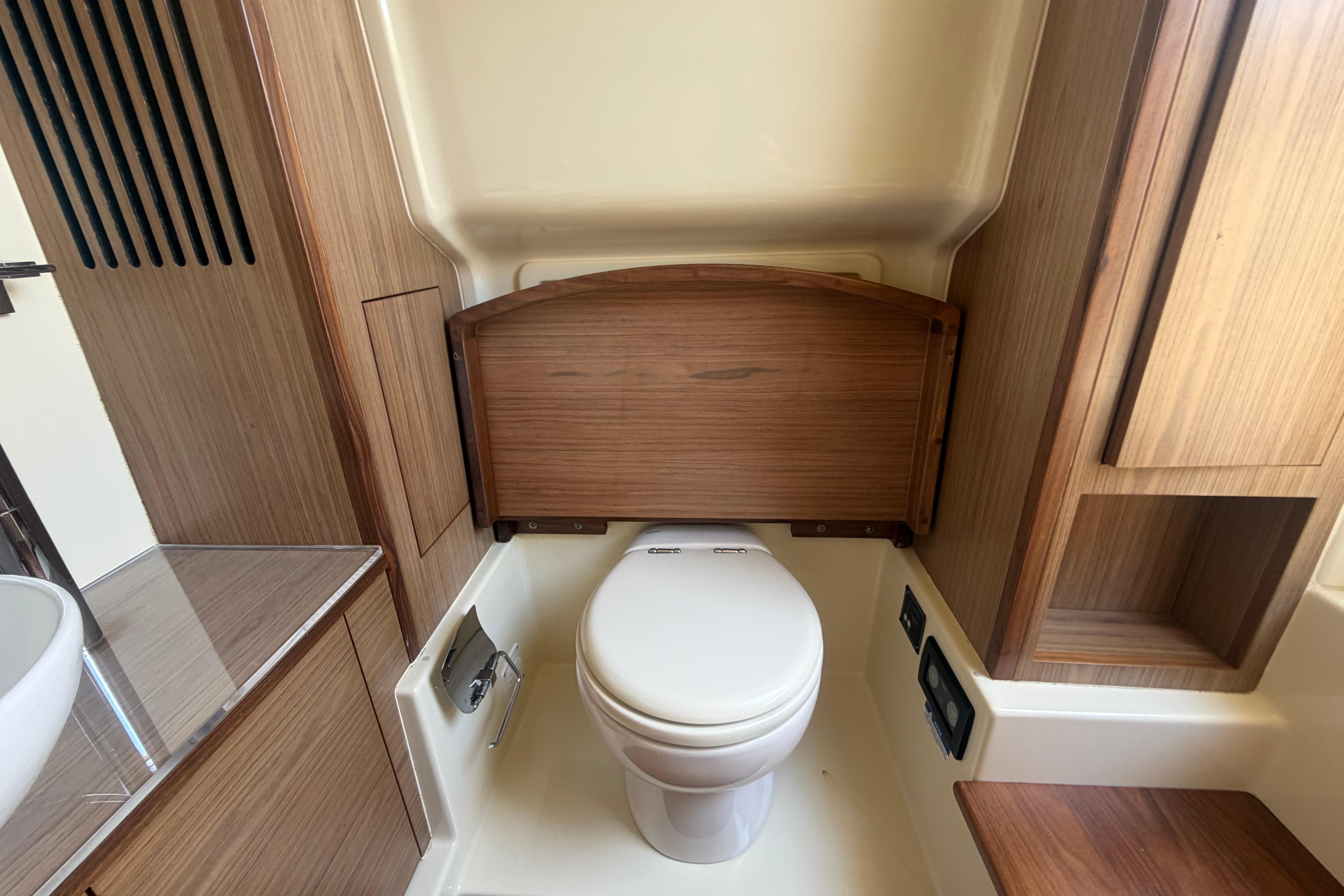 2017 Chris-Craft Catalina 34 boat bathroom with wooden cabinetry and modern toilet.