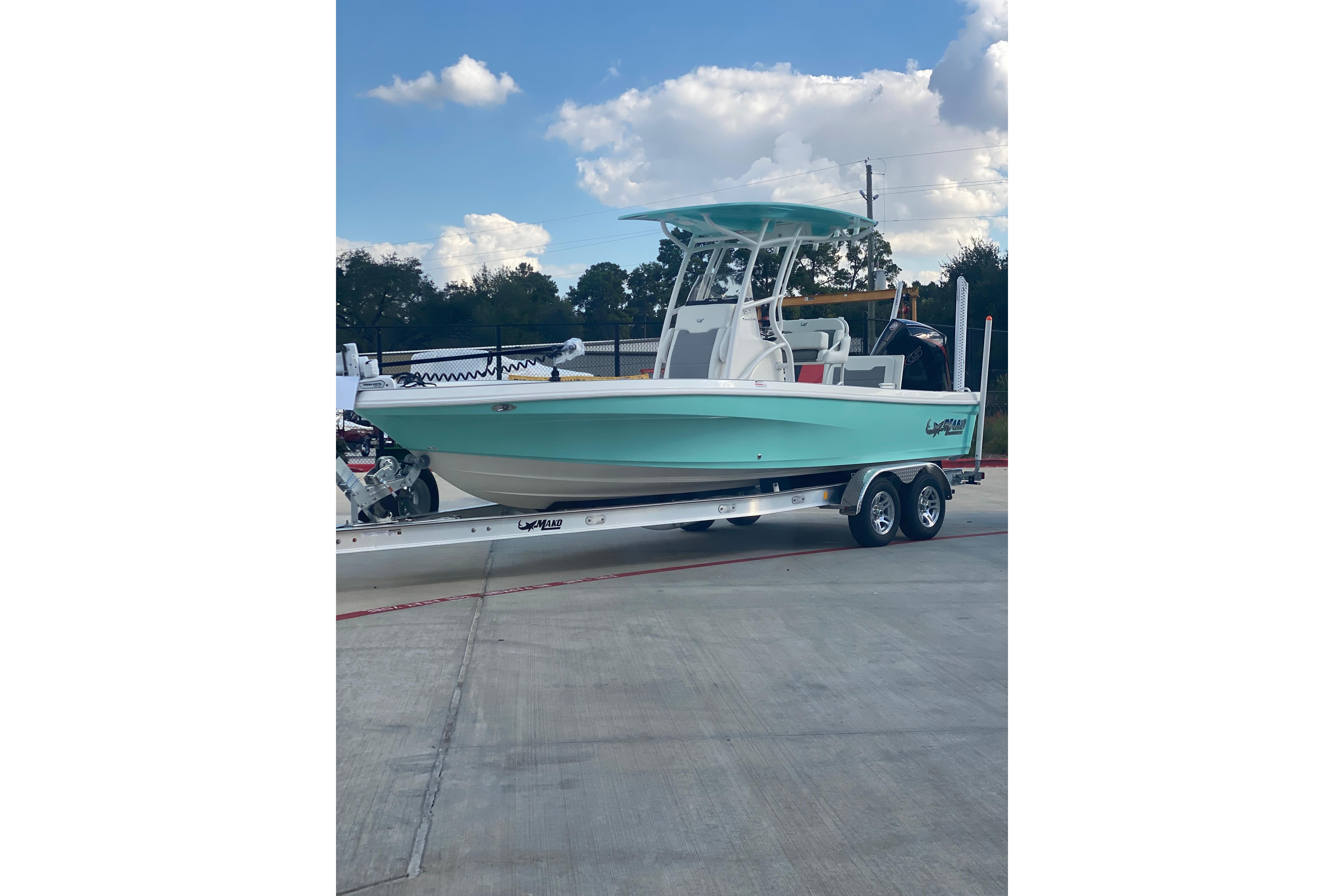 2026 Mako 24 APEX boat on trailer, parked outdoors under a partly cloudy sky.