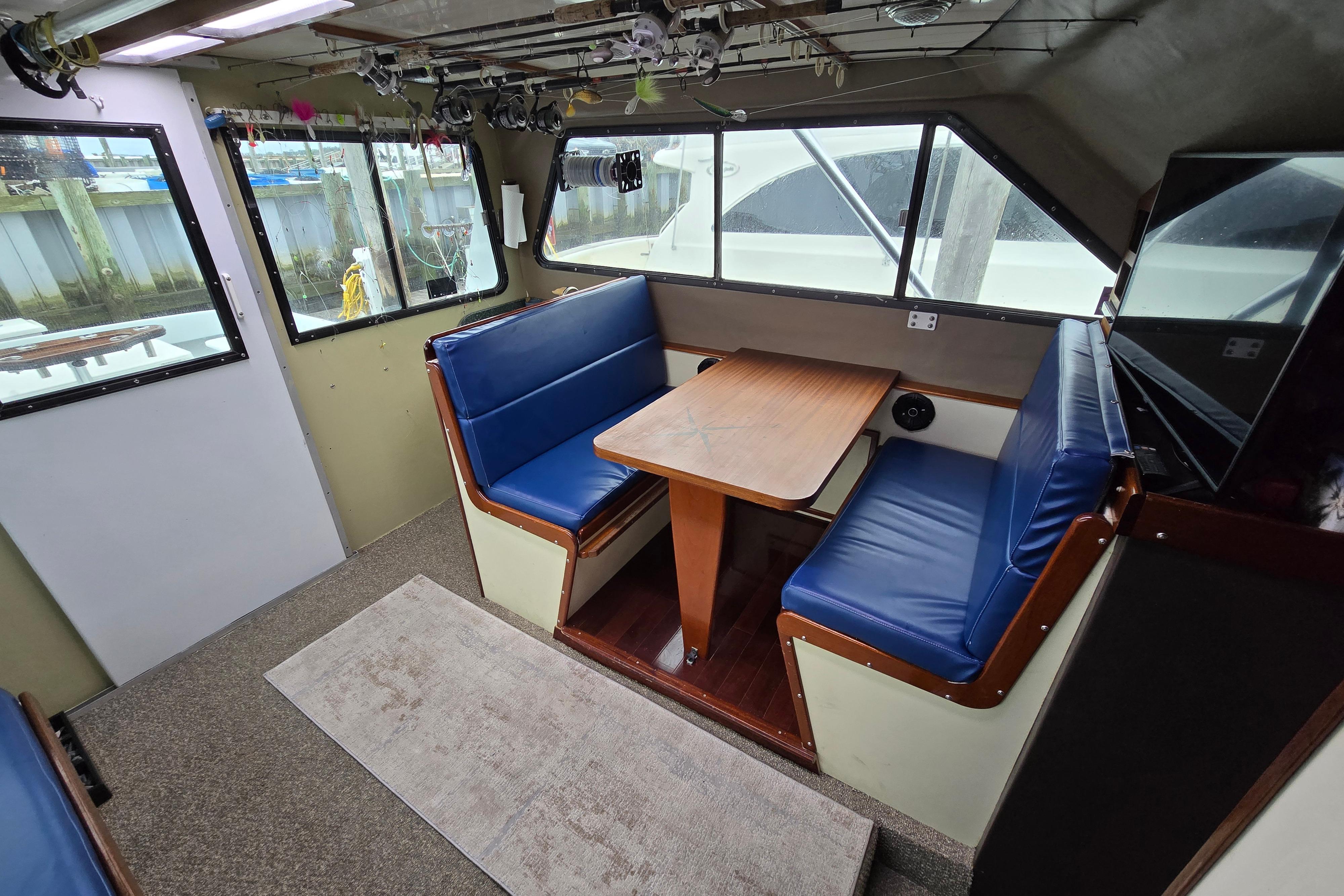 Interior of 2000 Custom 42 JM Sportfish boat with blue seating and wooden table.