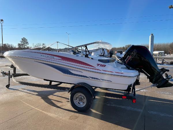 2024 Tahoe T18 boat on trailer, white with red and blue accents, parked outdoors.
