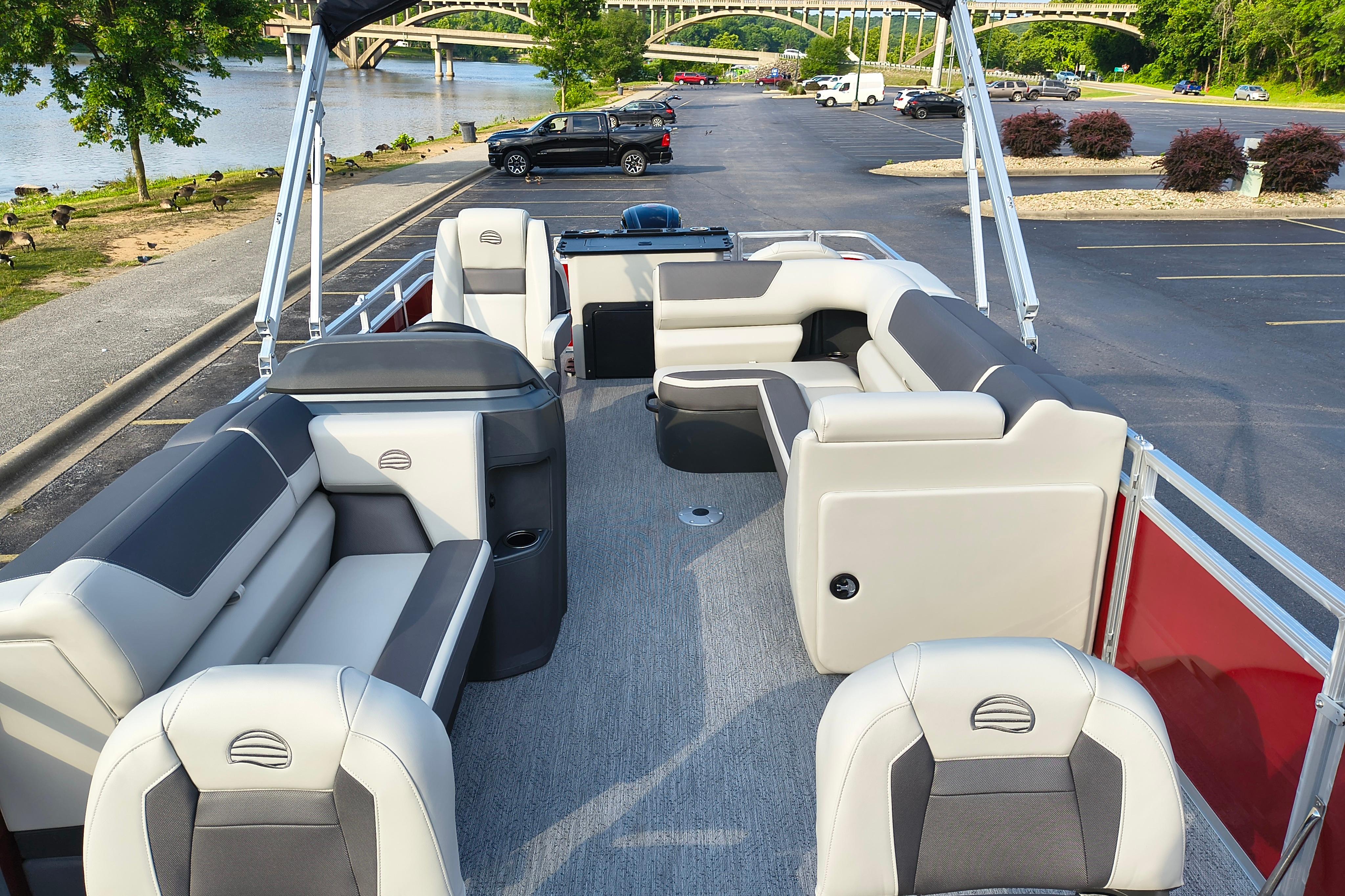 2026 Sun Tracker Fishin' Barge 22 DLX pontoon boat with spacious seating and scenic river backdrop.