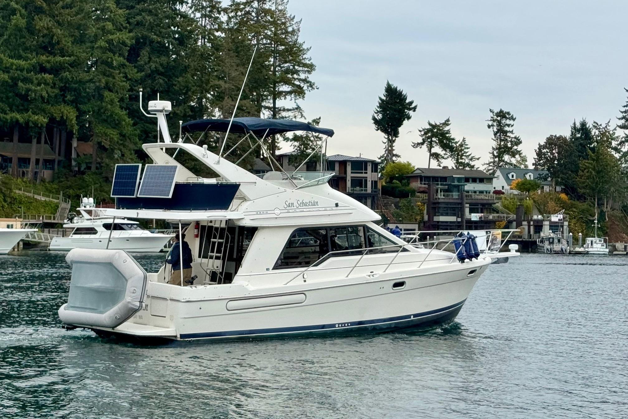 1998 Bayliner 3388 Command Bridge Motoryacht cruising near waterfront homes and trees.