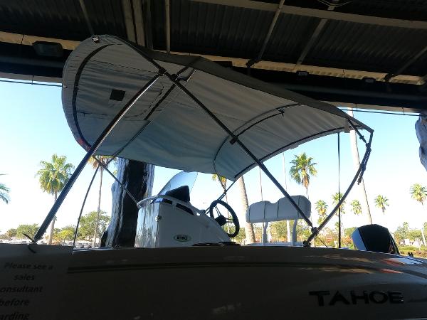 2023 Tahoe 2150 CC boat with canopy, parked indoors, palm trees visible outside.