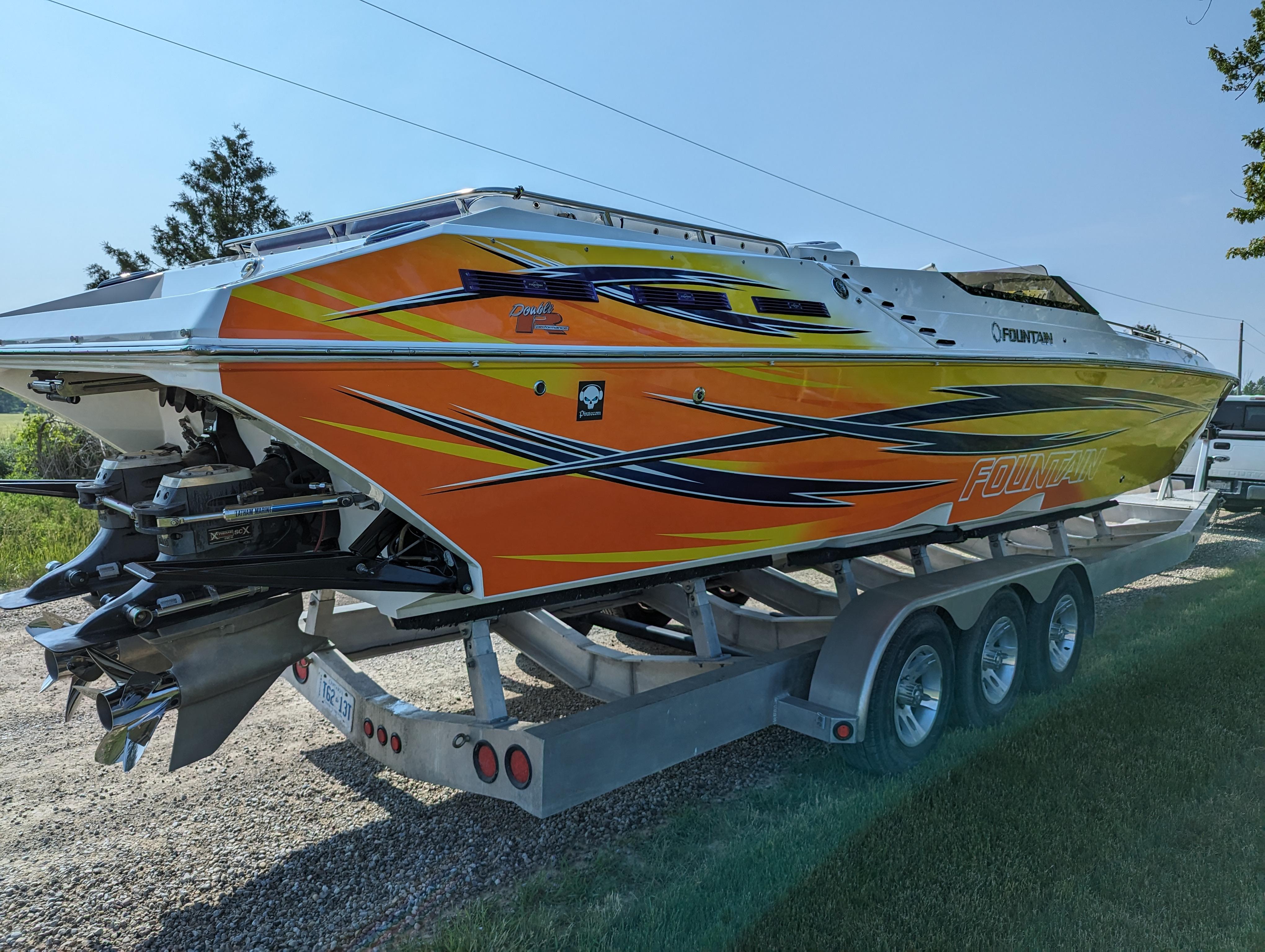 2006 Fountain 42 speedboat with vibrant orange and yellow graphics on a trailer.