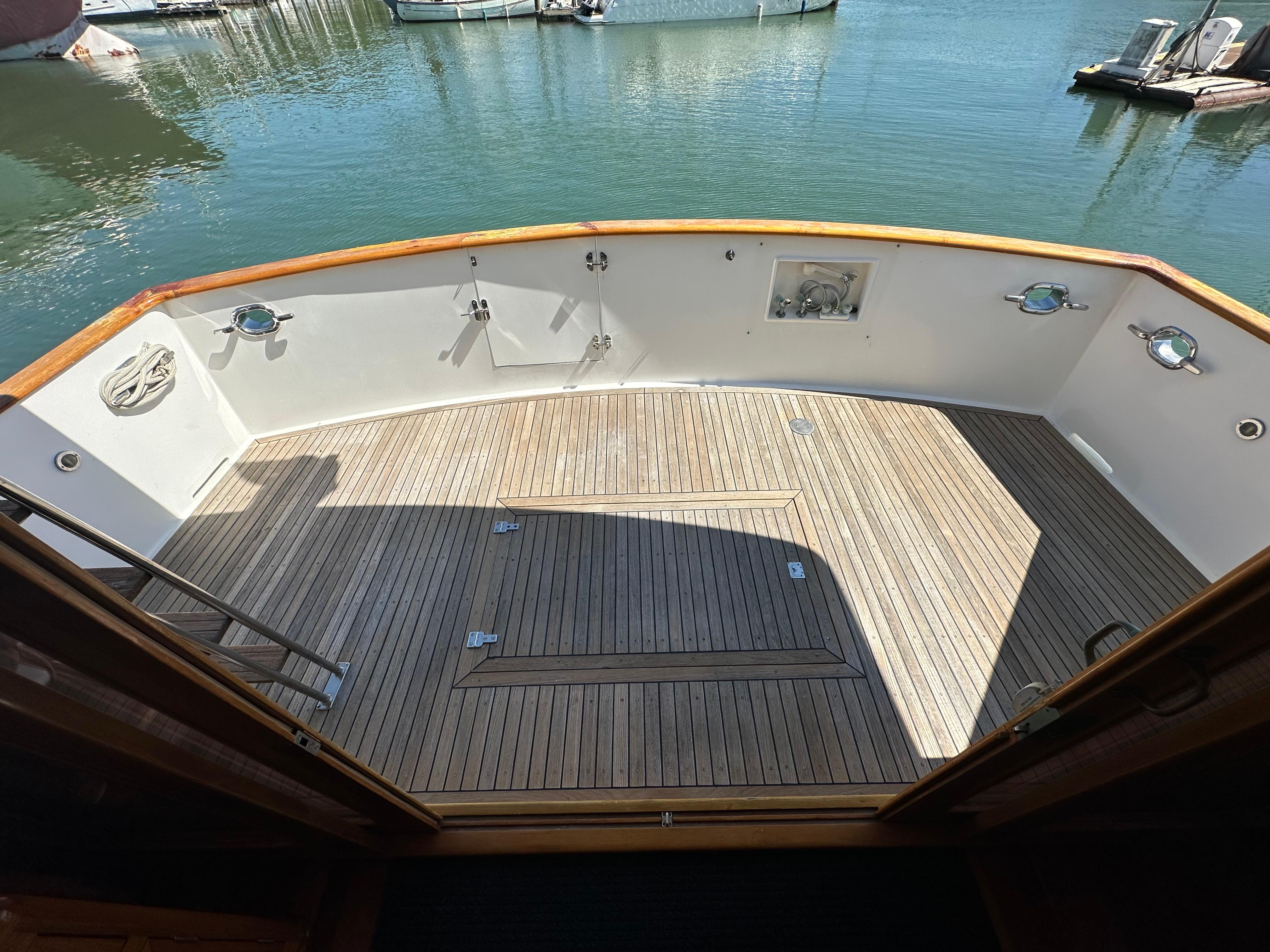 1985 Ocean Alexander Pilothouse yacht deck with wooden flooring and marina view.