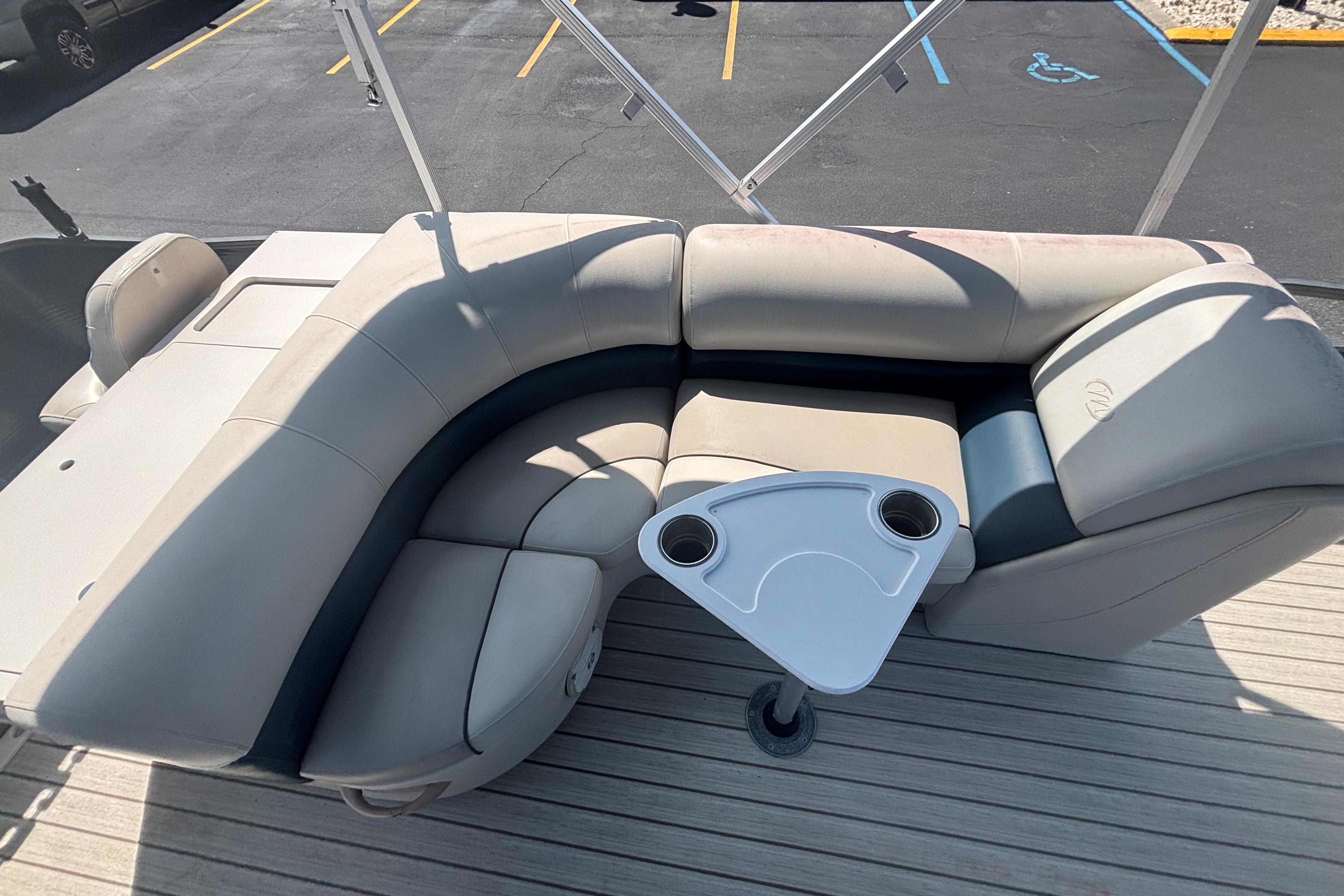 2015 Manitou 20 Oasis Angler boat with beige seating and cupholder table.