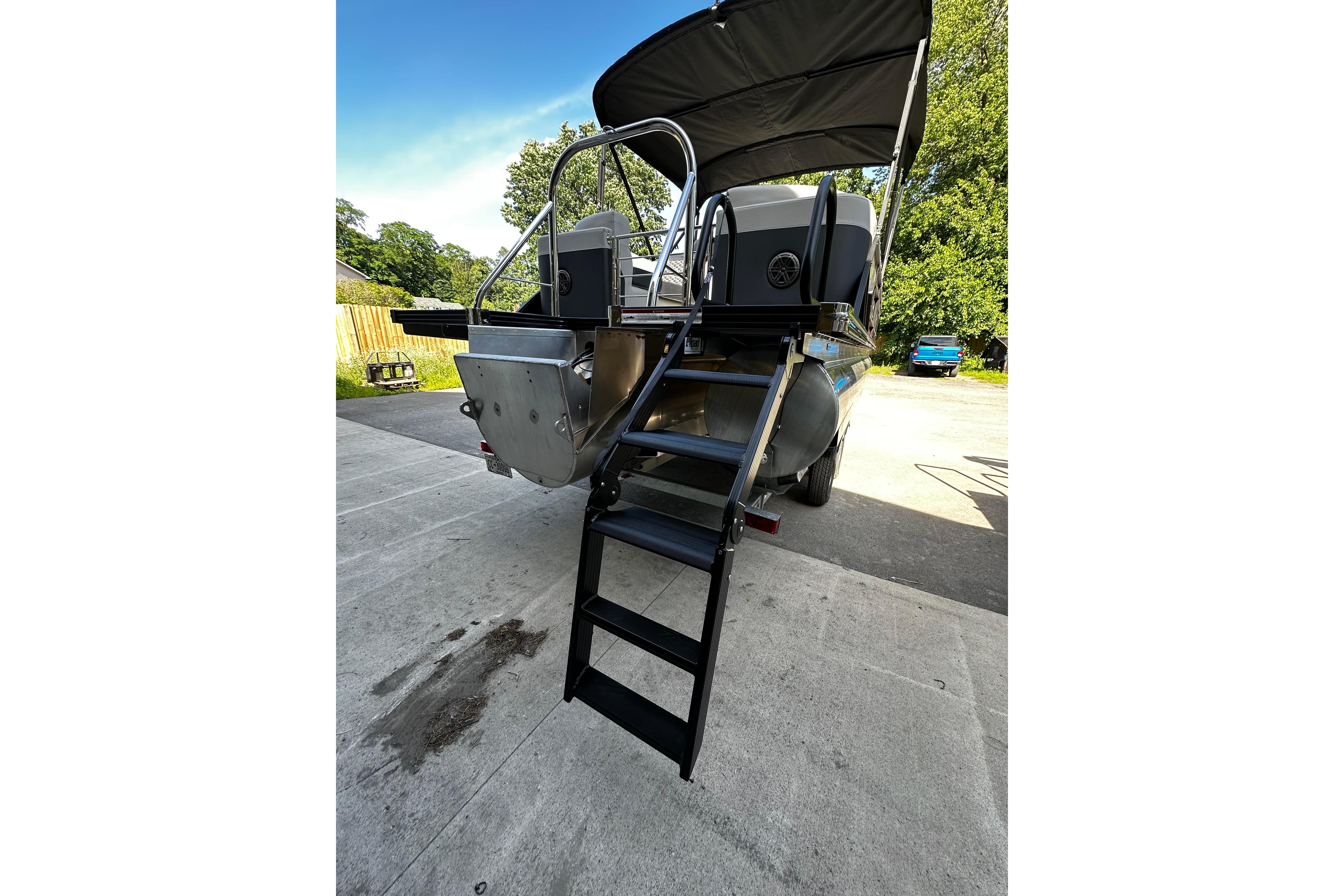 2027 Manitou 25 Encore RF pontoon boat with rear ladder and canopy, parked outdoors.