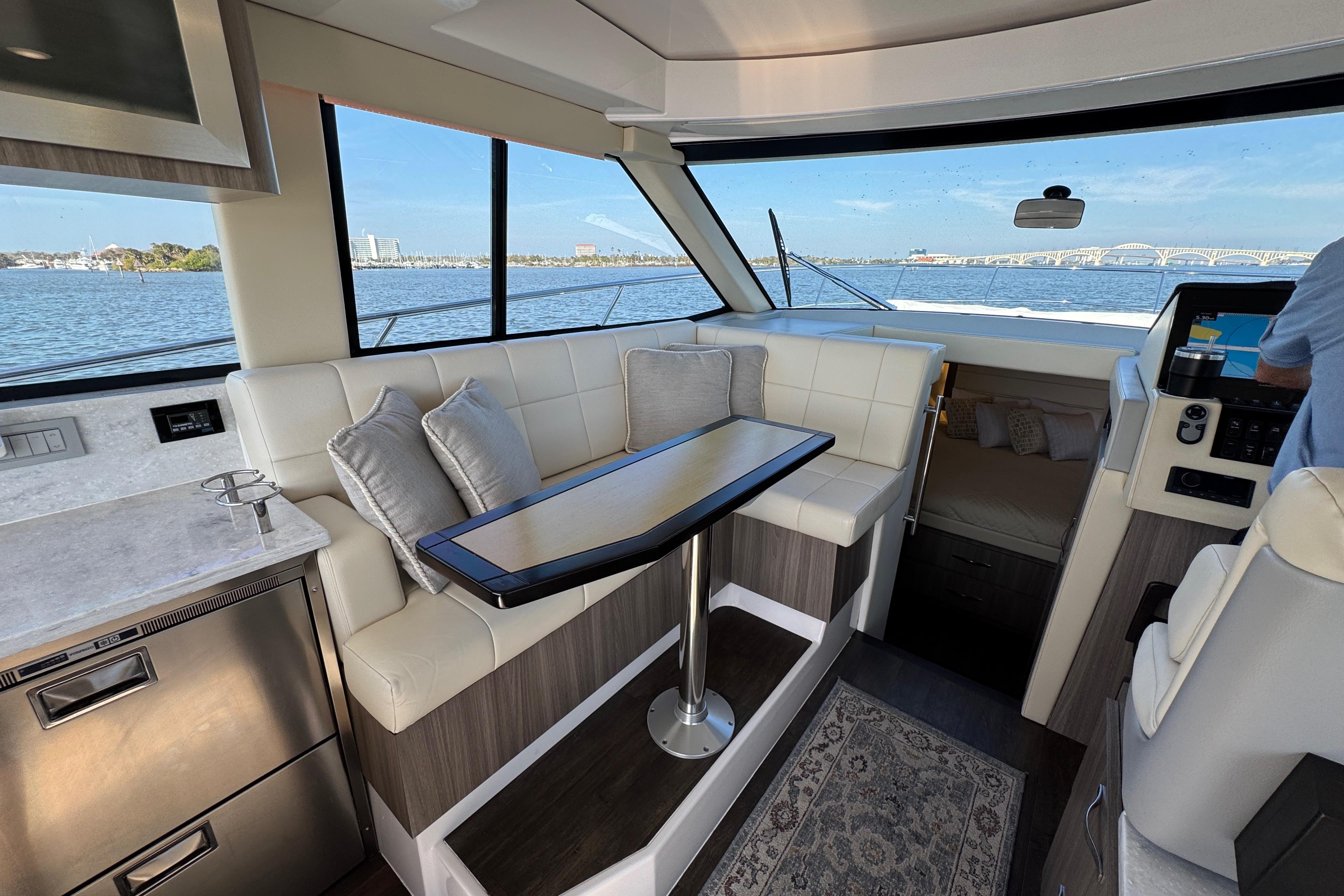 Interior of 2021 Regal 38 XO yacht with seating, table, and scenic water view.