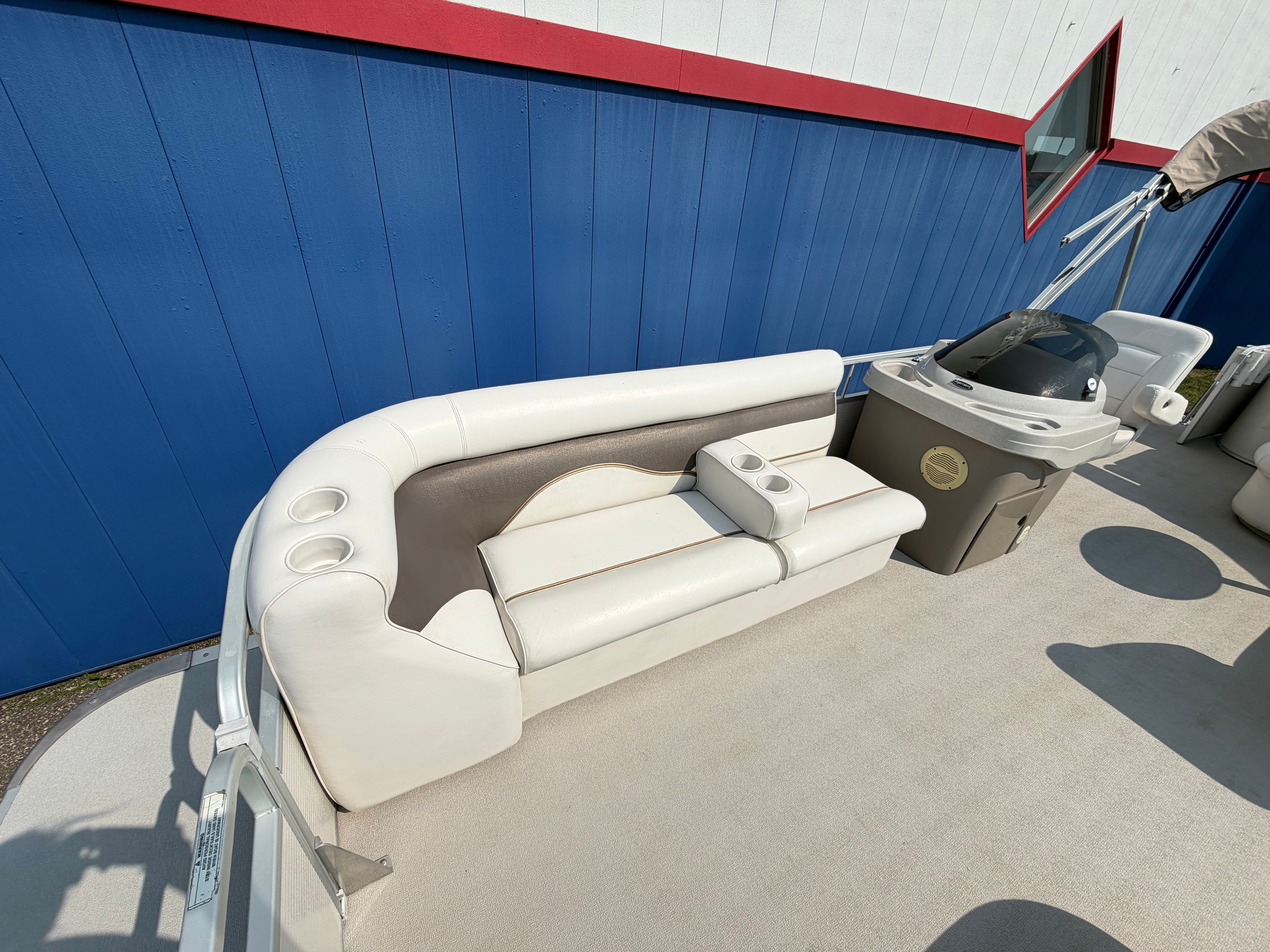 Premier 225 Sunsation 2007 with beige and brown seating area, blue wall in the background.