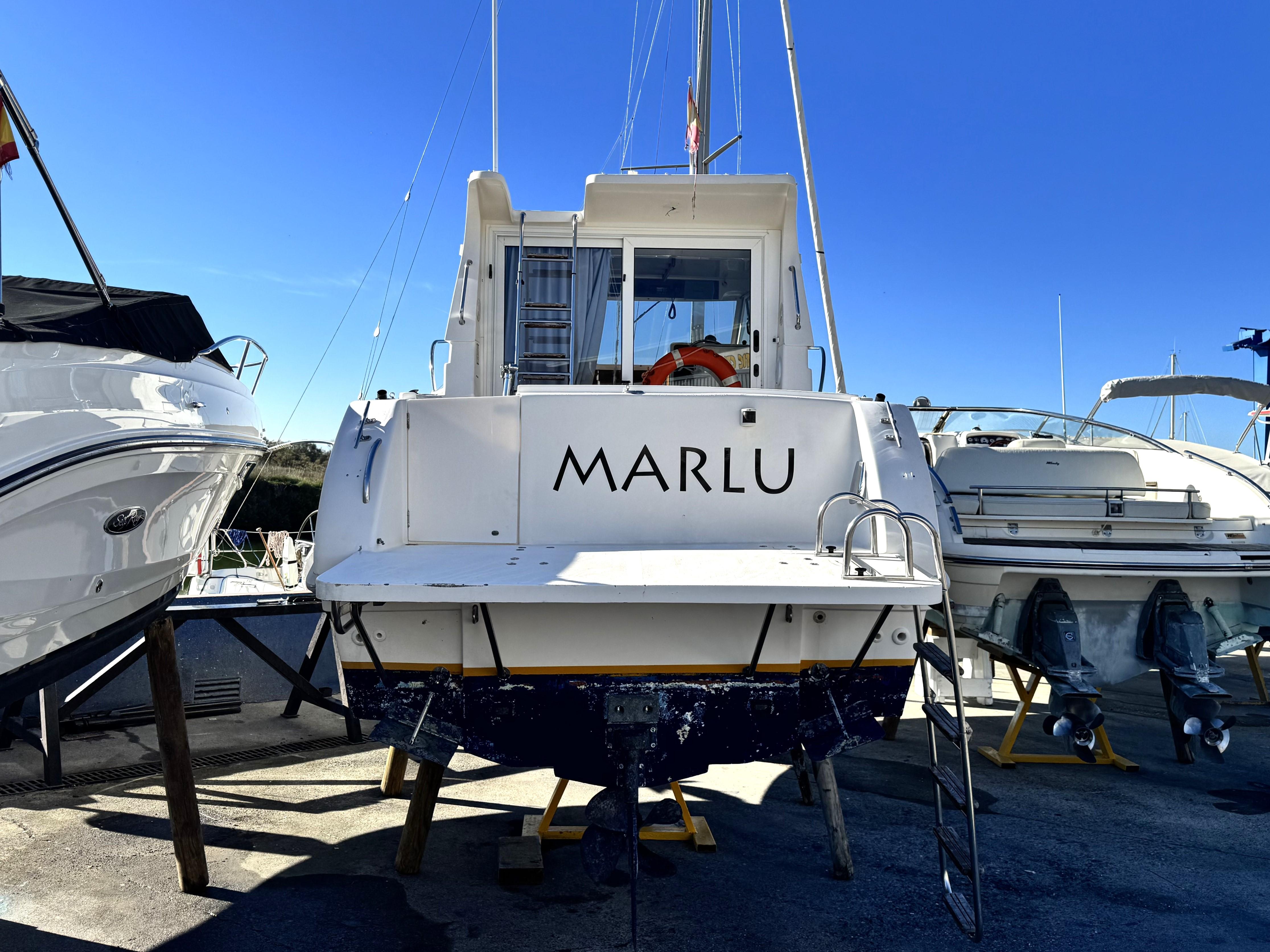 RIO 800 Cabin Fish 2002 boat named "MARLU" docked with clear blue sky background.