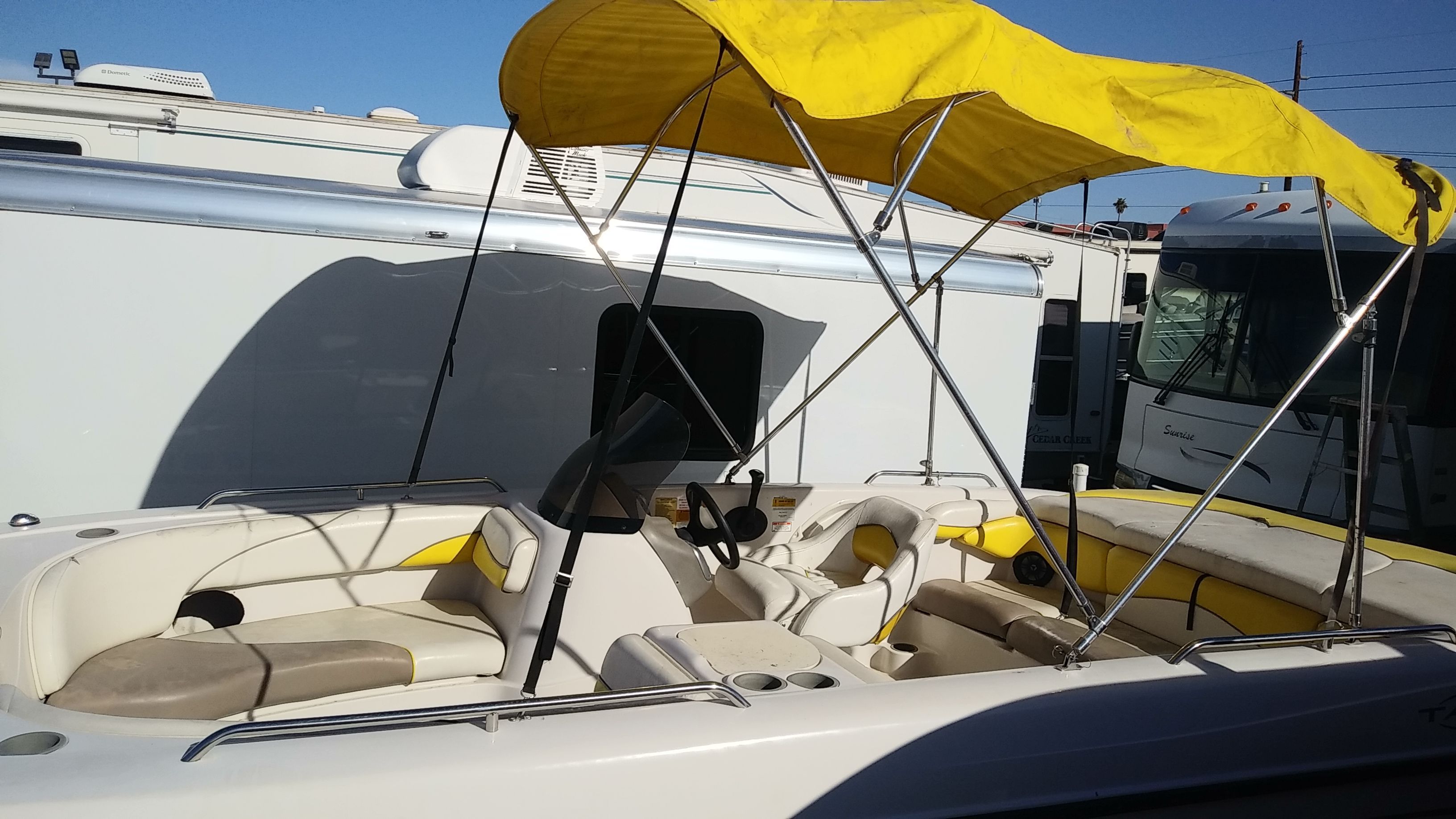2004 Tracker Tahoe boat with yellow canopy, parked beside RVs.