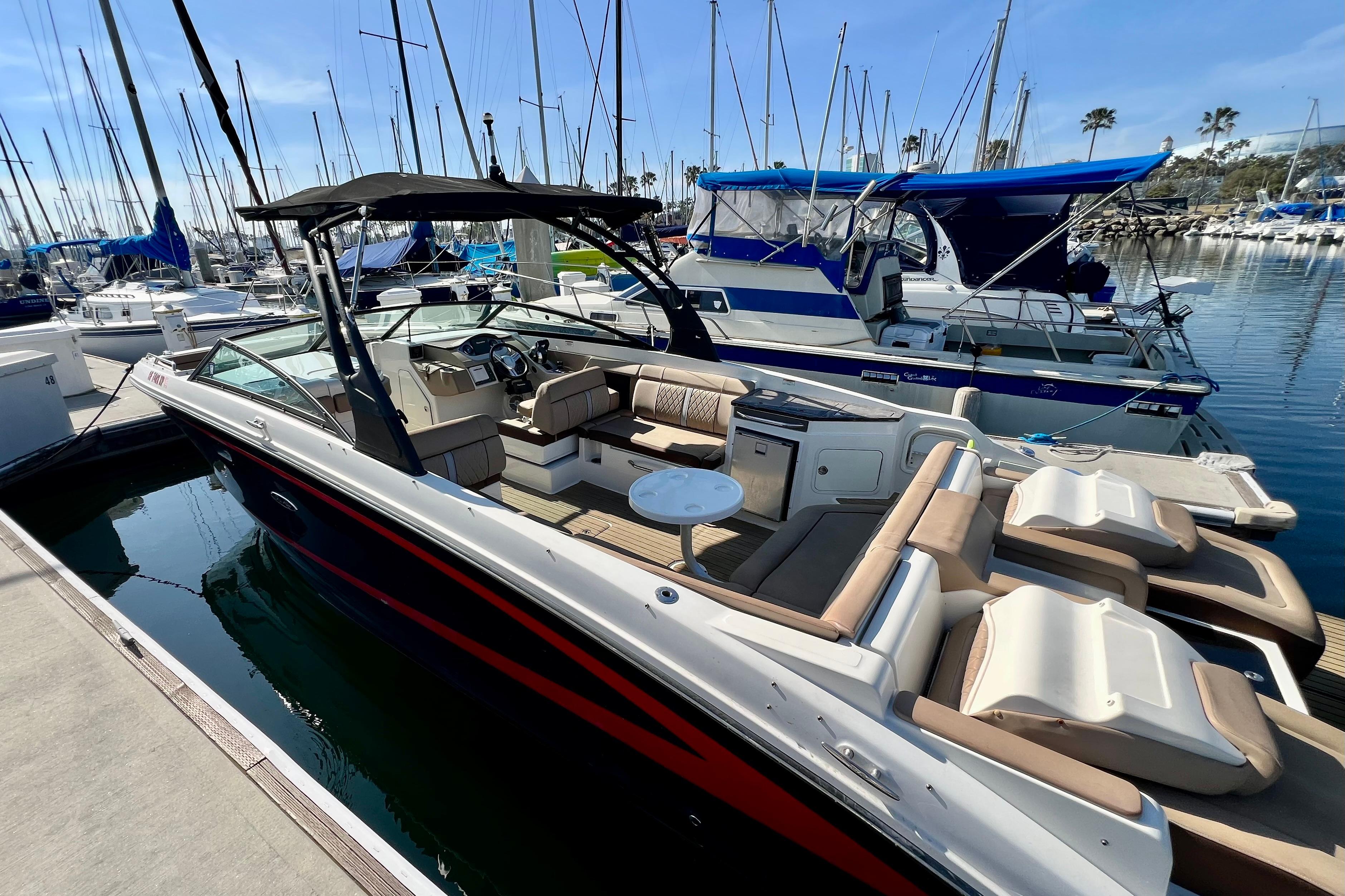 2016 Sea Ray 290 Sundeck Outboard docked in a marina, surrounded by sailboats.