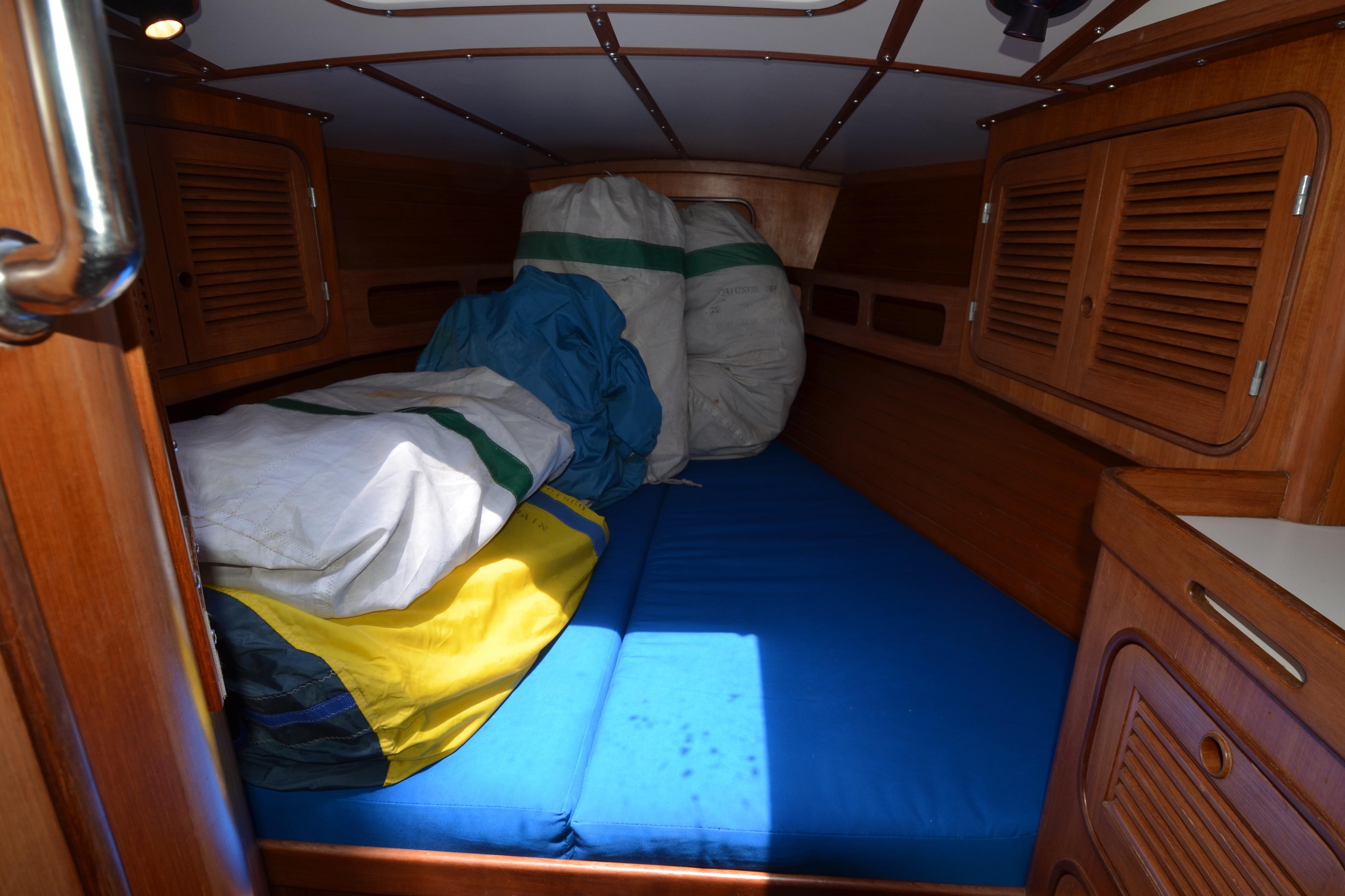 Cozy cabin interior of 1987 Norseman 400 sailboat with wooden finish and colorful sails.