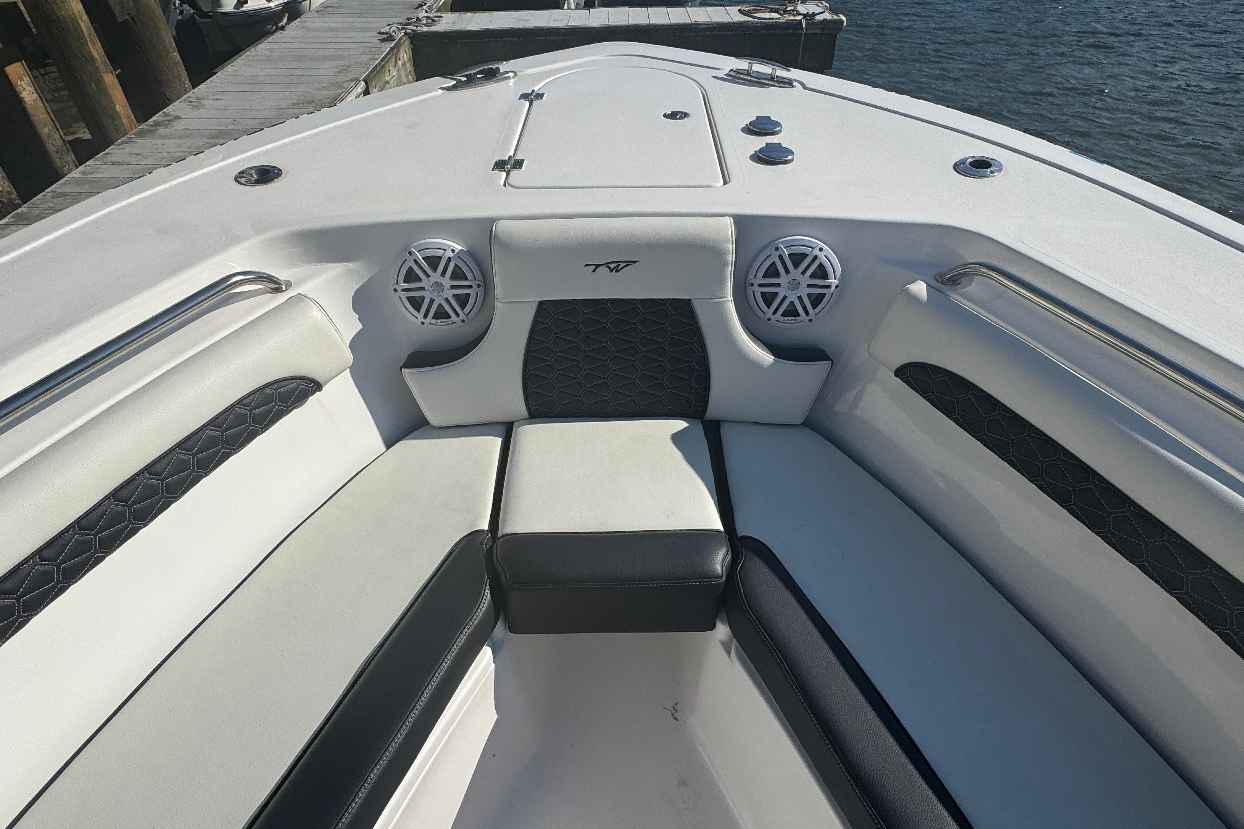 2025 Tidewater 232 LXF boat interior with cushioned seating and speakers, docked by the water.