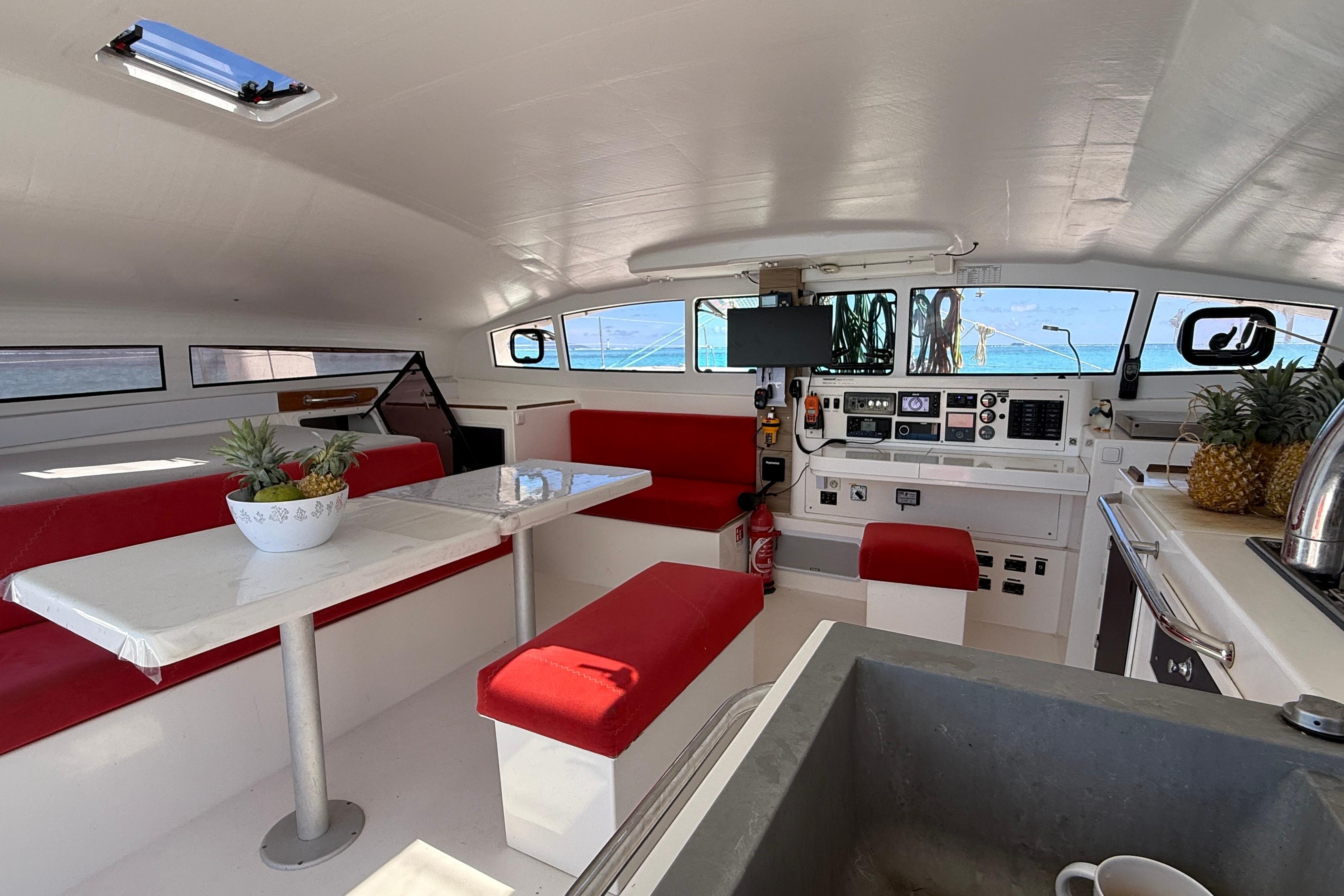 Interior of 2020 Marsaudon Composites TS 42 catamaran with red seating and modern navigation equipment.