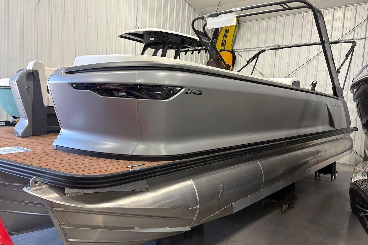 2023 Manitou EXPLORE 26 SHP 575 pontoon boat in a showroom setting.