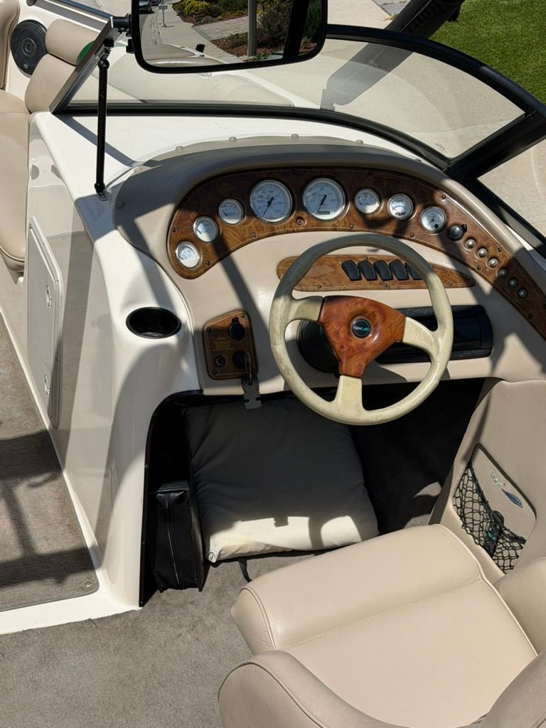 The cockpit of a 1999 Tigé 21V boat with a wooden dashboard and cream-colored seats.