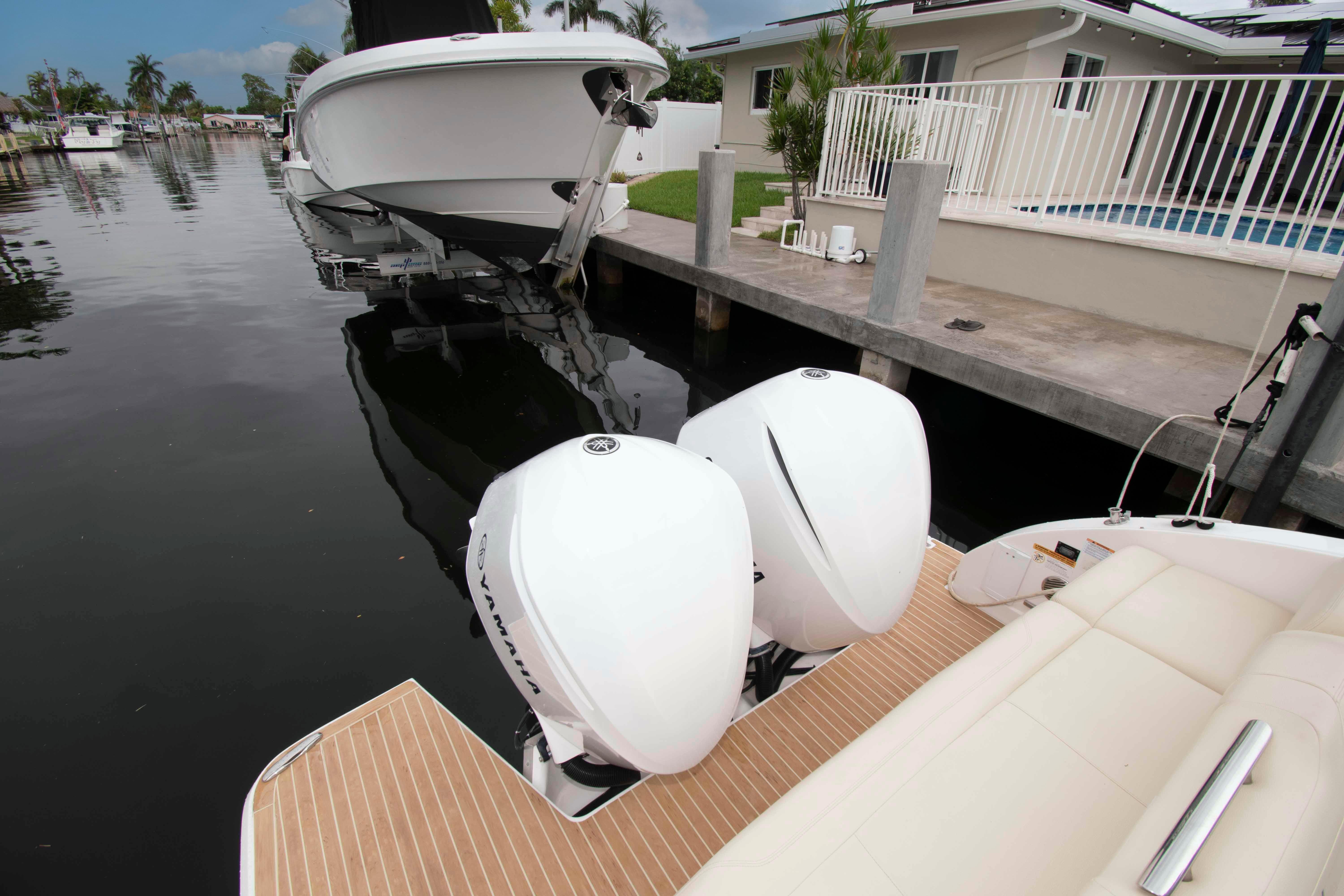 2019 Regal 33 OBX boat with twin Yamaha outboard engines docked by a canal.