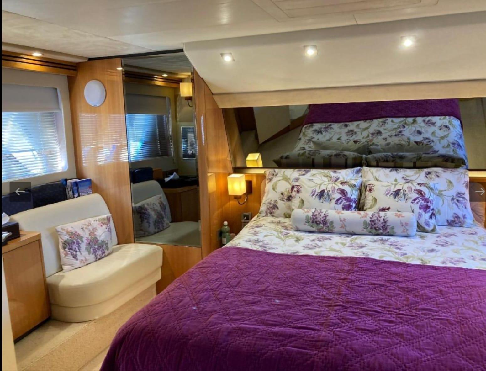 Luxurious bedroom interior of 2005 Sealine T60 yacht with floral bedding and ambient lighting.