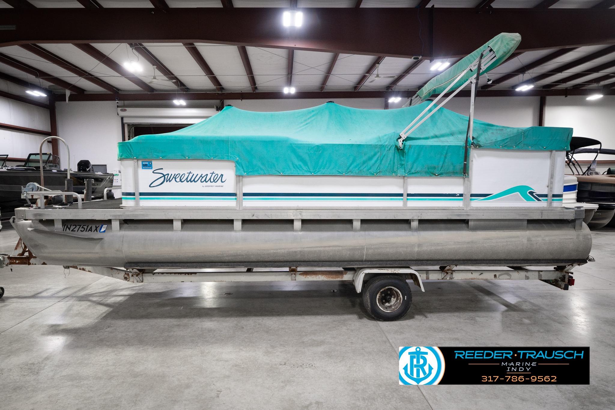 1992 Godfrey Sweetwater pontoon boat with teal cover in indoor storage facility.