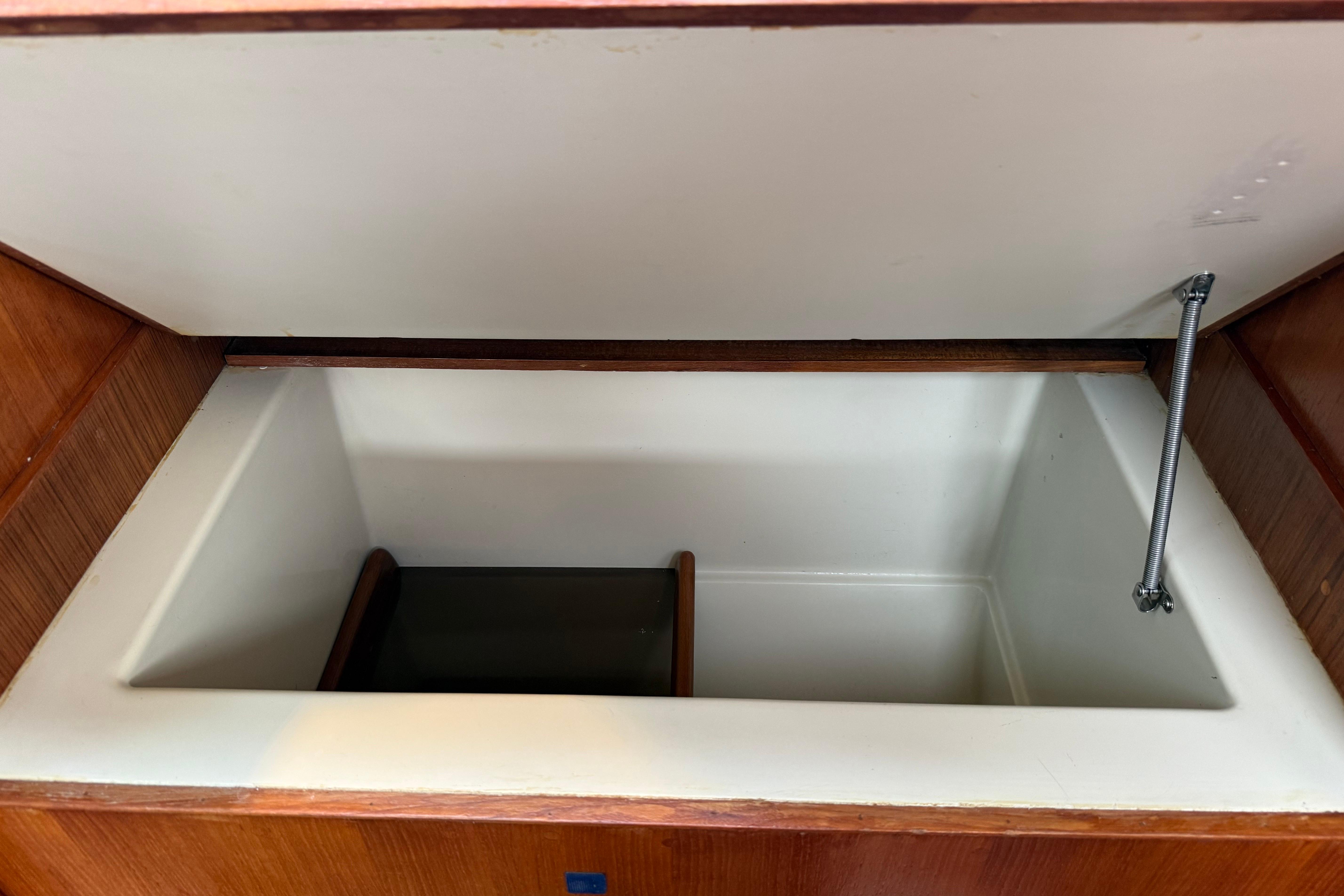 Open storage compartment inside 1988 Ericson 32-200 sailboat, featuring wooden trim and hydraulic support.