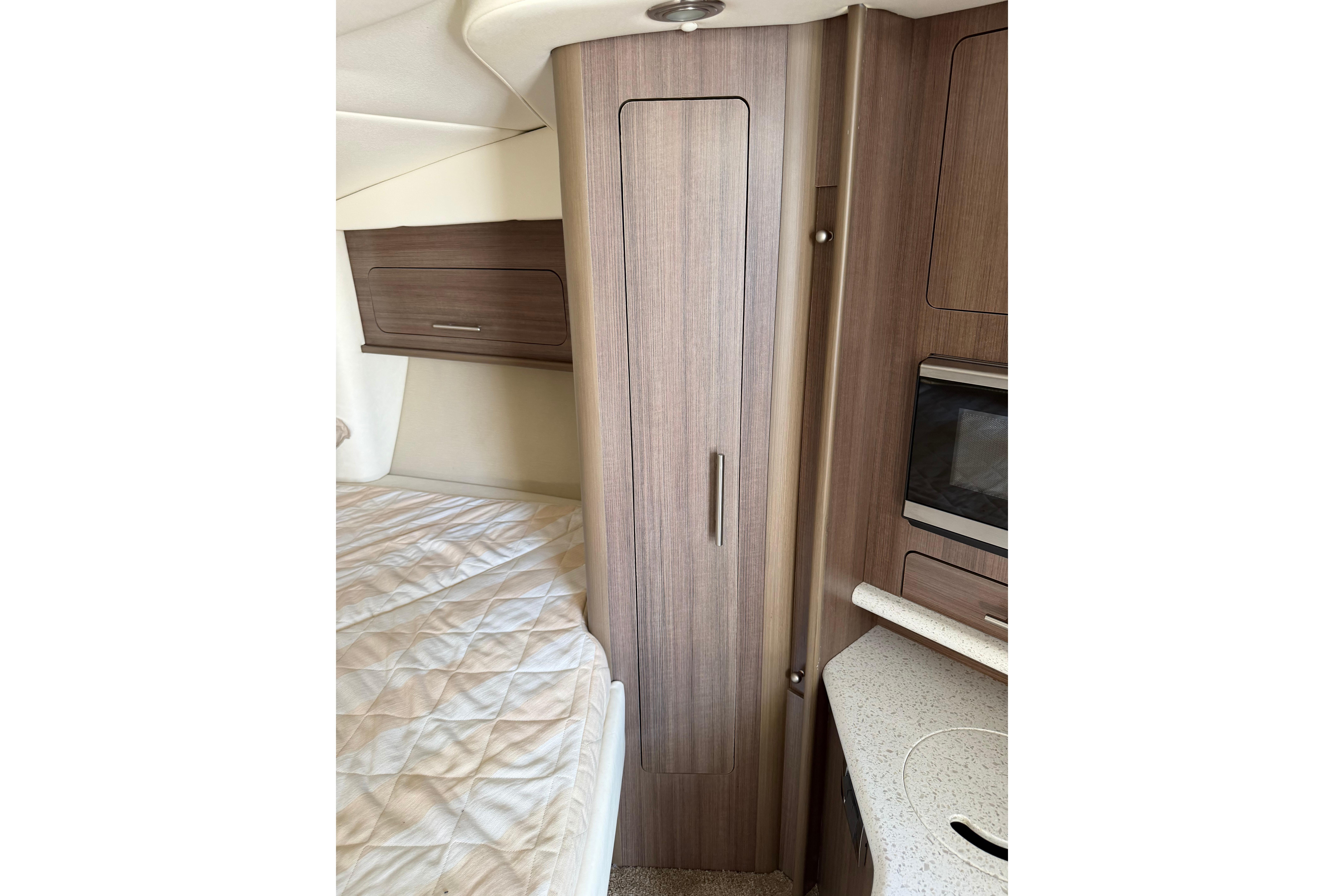 2019 Rinker EX 320 cabin interior with wood cabinetry and bed.