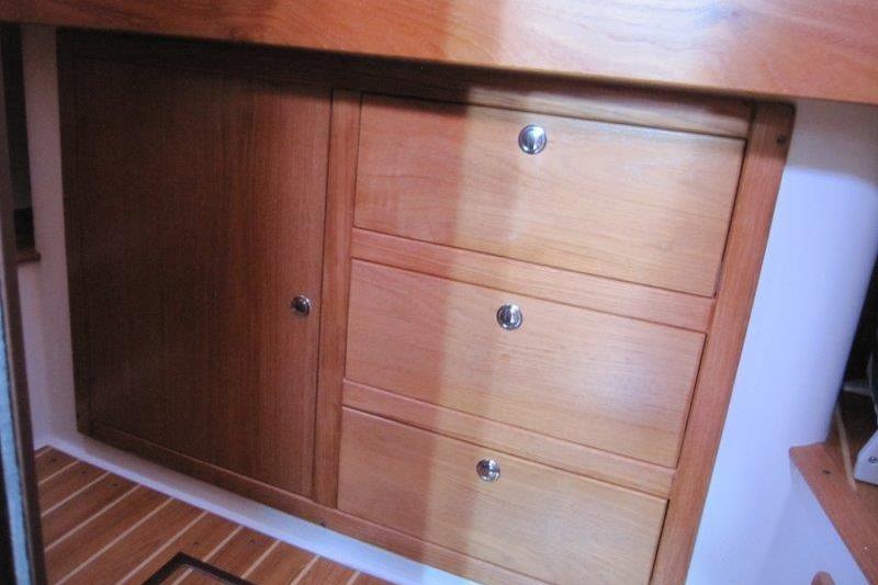 Wooden cabinetry inside a 2004 Catalina 350 MkII sailboat, featuring drawers and a cabinet door.