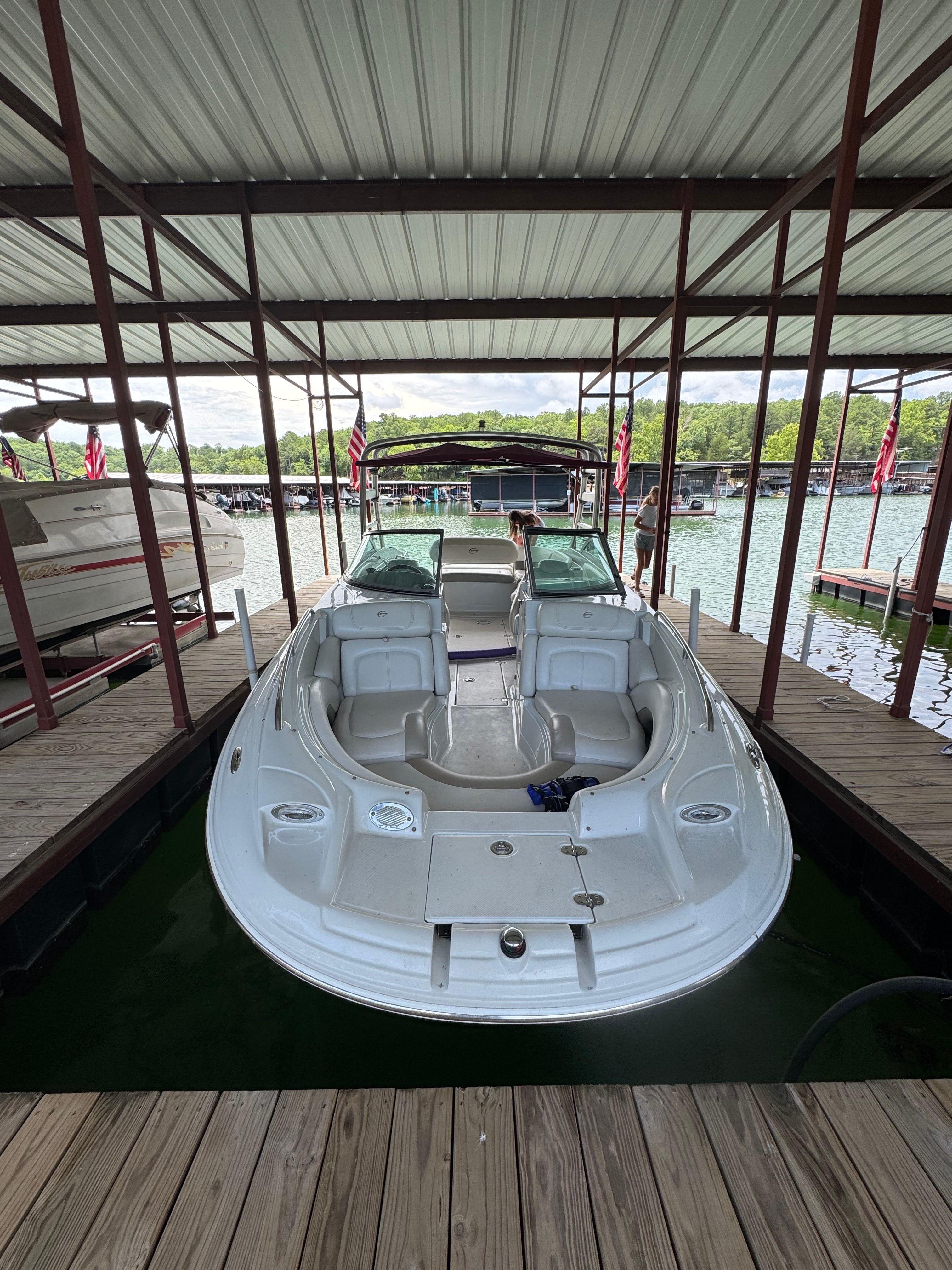 A 2008 Crownline 252EX boat is docked under a covered slip on the water.