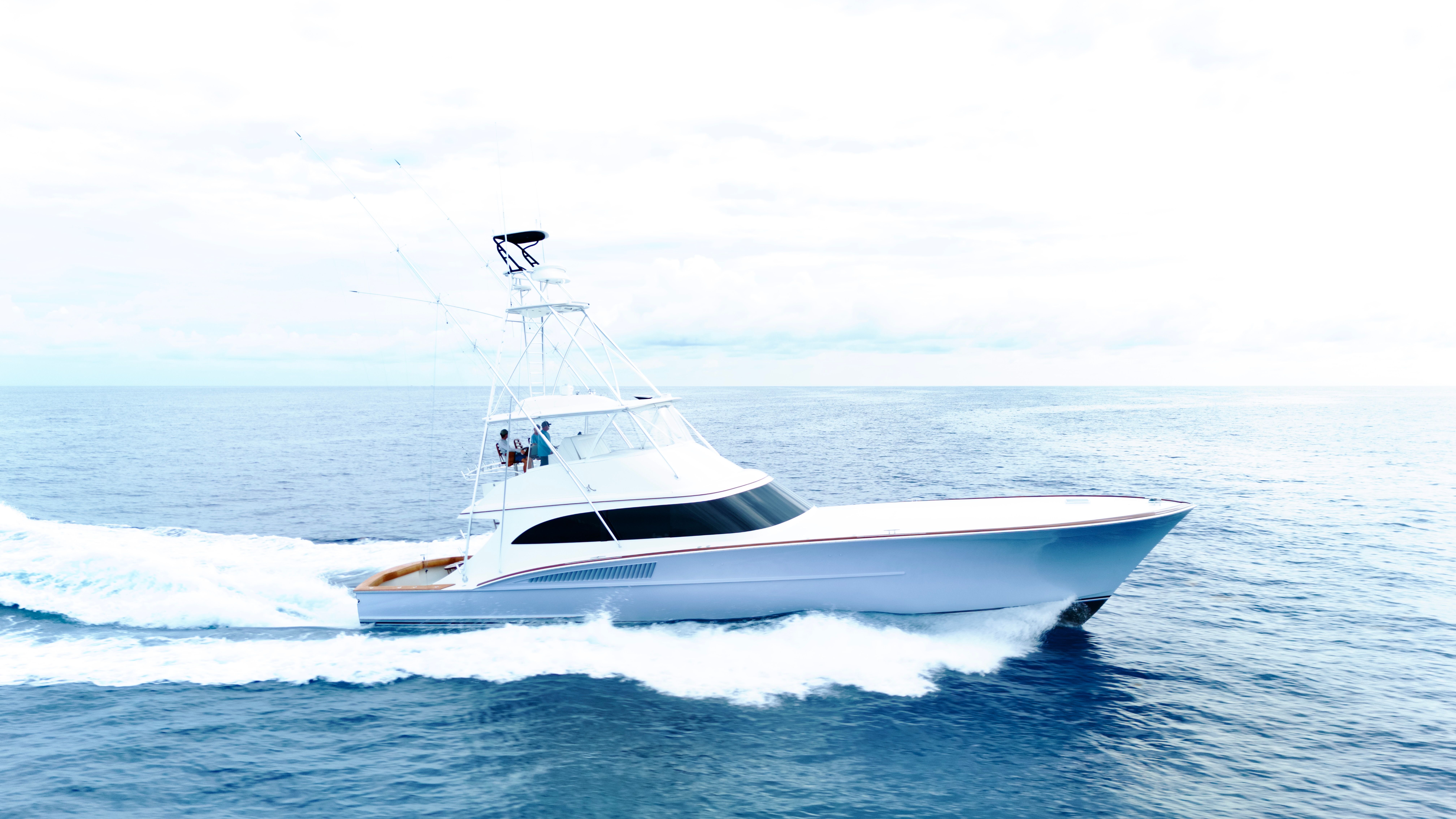 A sleek sportfishing boat speeds across the open sea.