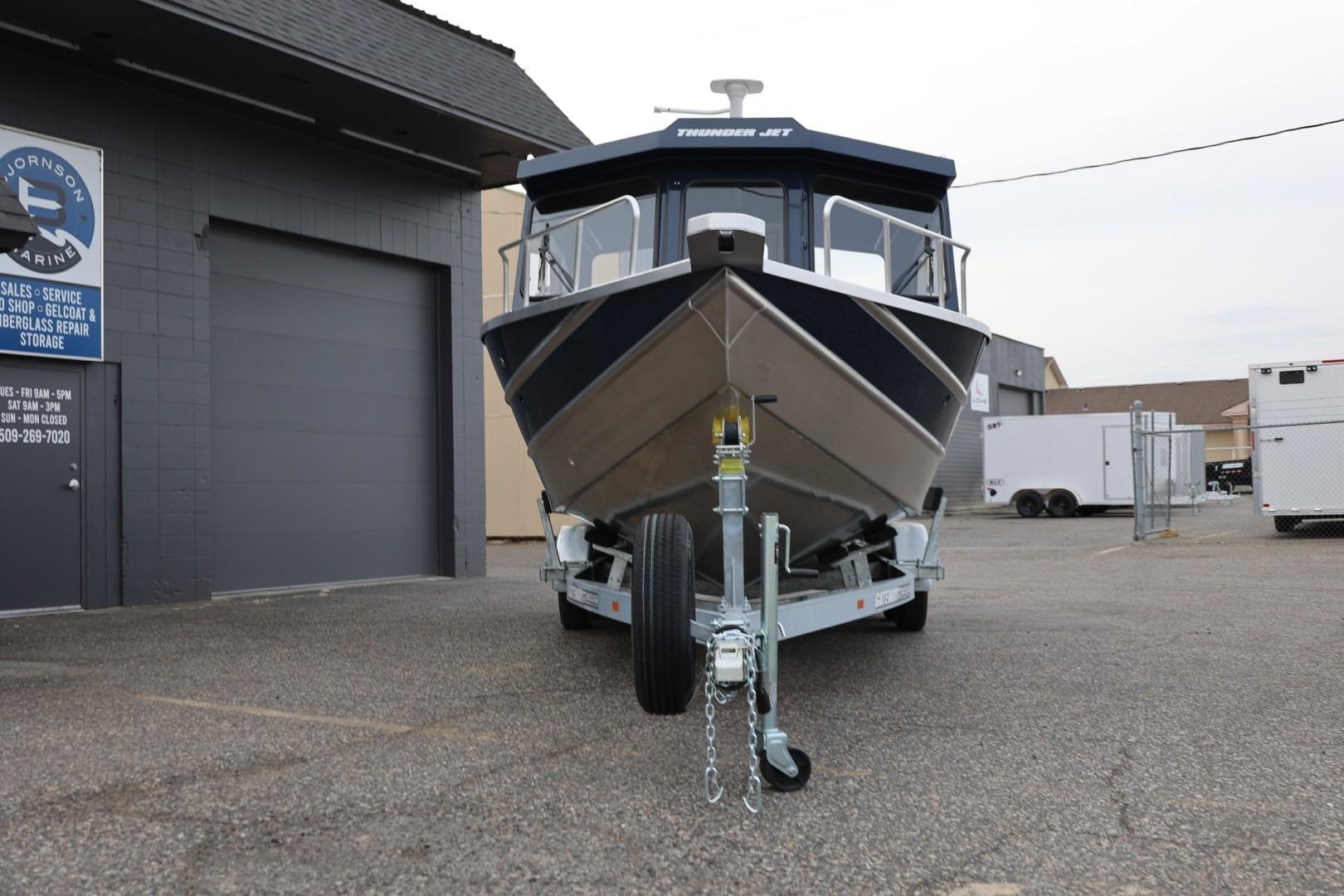 2026 Thunder Jet 24 Alexis Pro boat on trailer outside marine service shop.