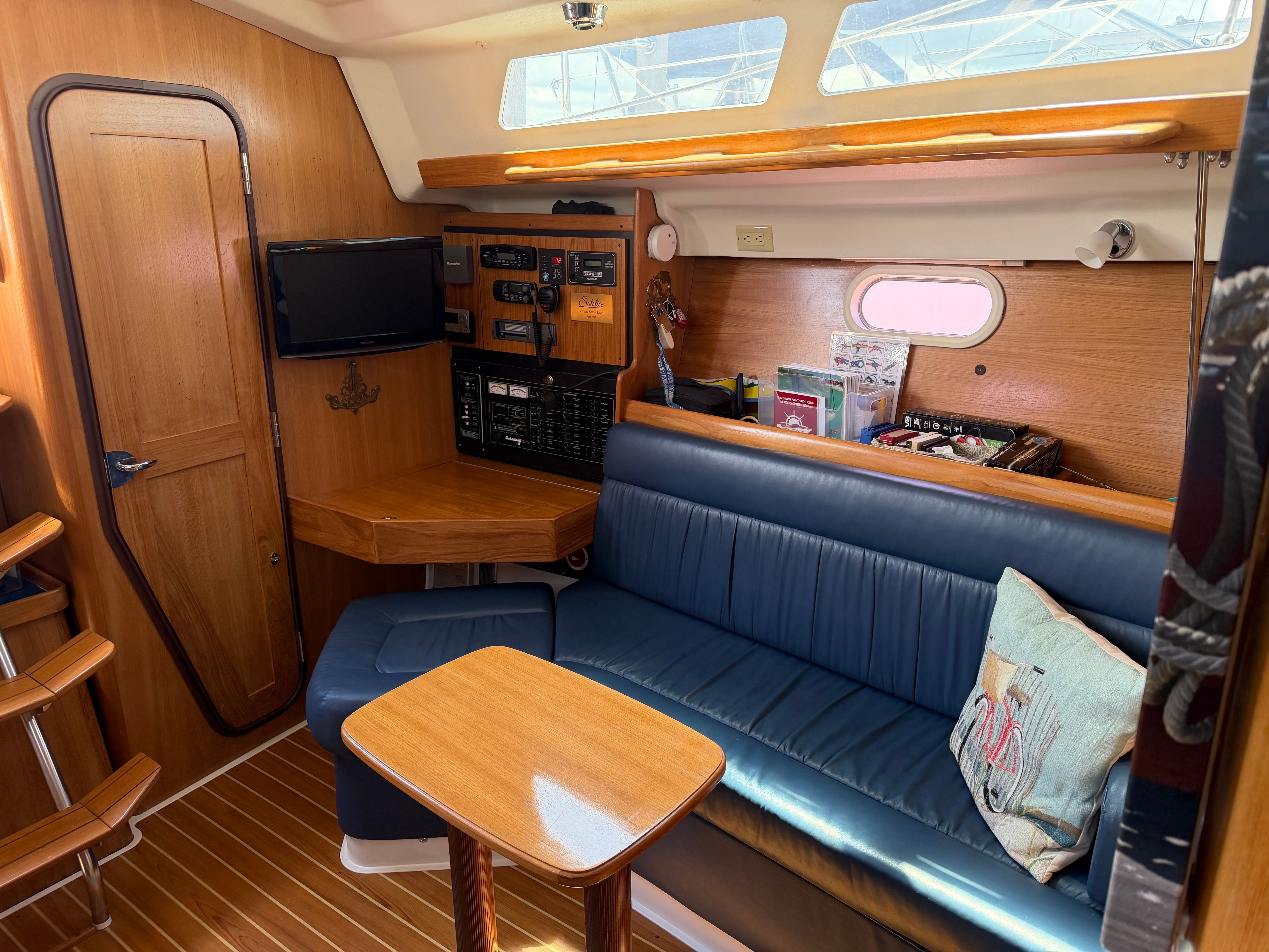 Interior of a 2004 Catalina 350 with blue seating and a wooden table.