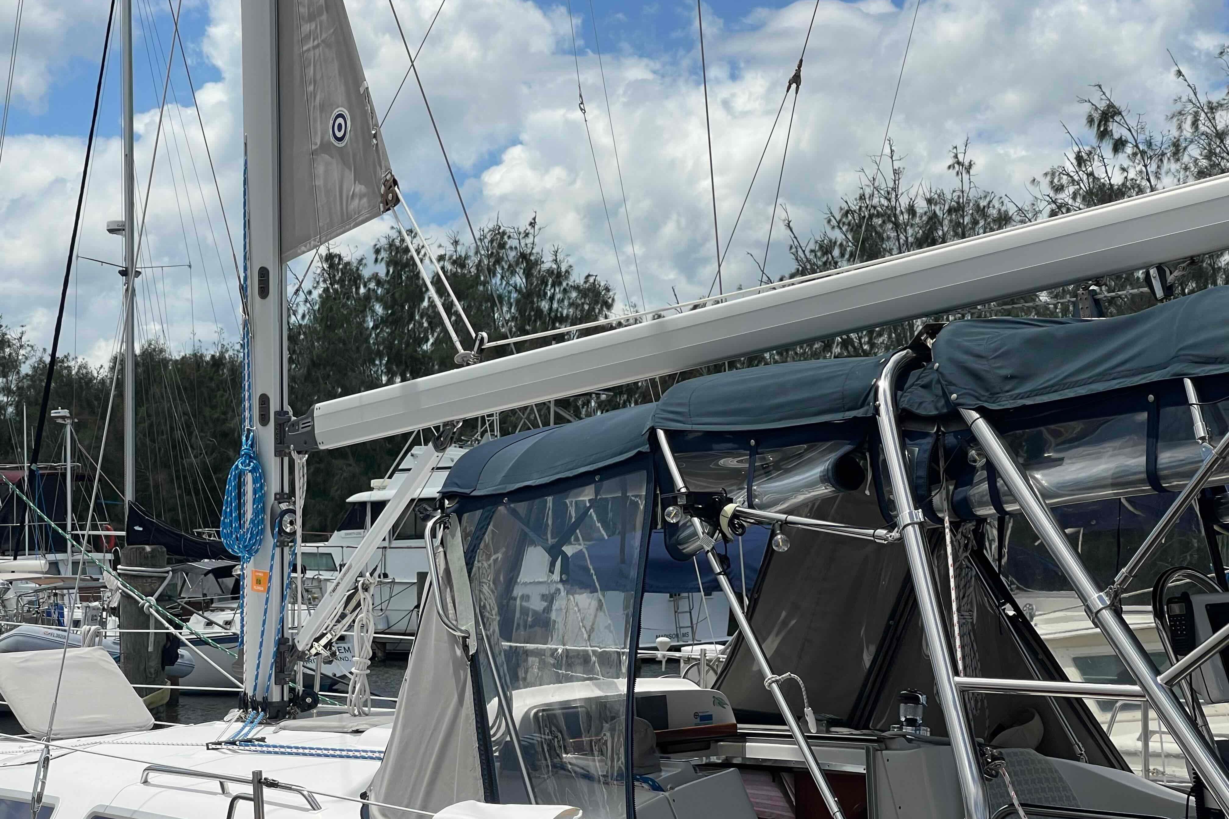 2004 Hunter 36 sailboat docked, featuring sails and canopy under a cloudy sky.