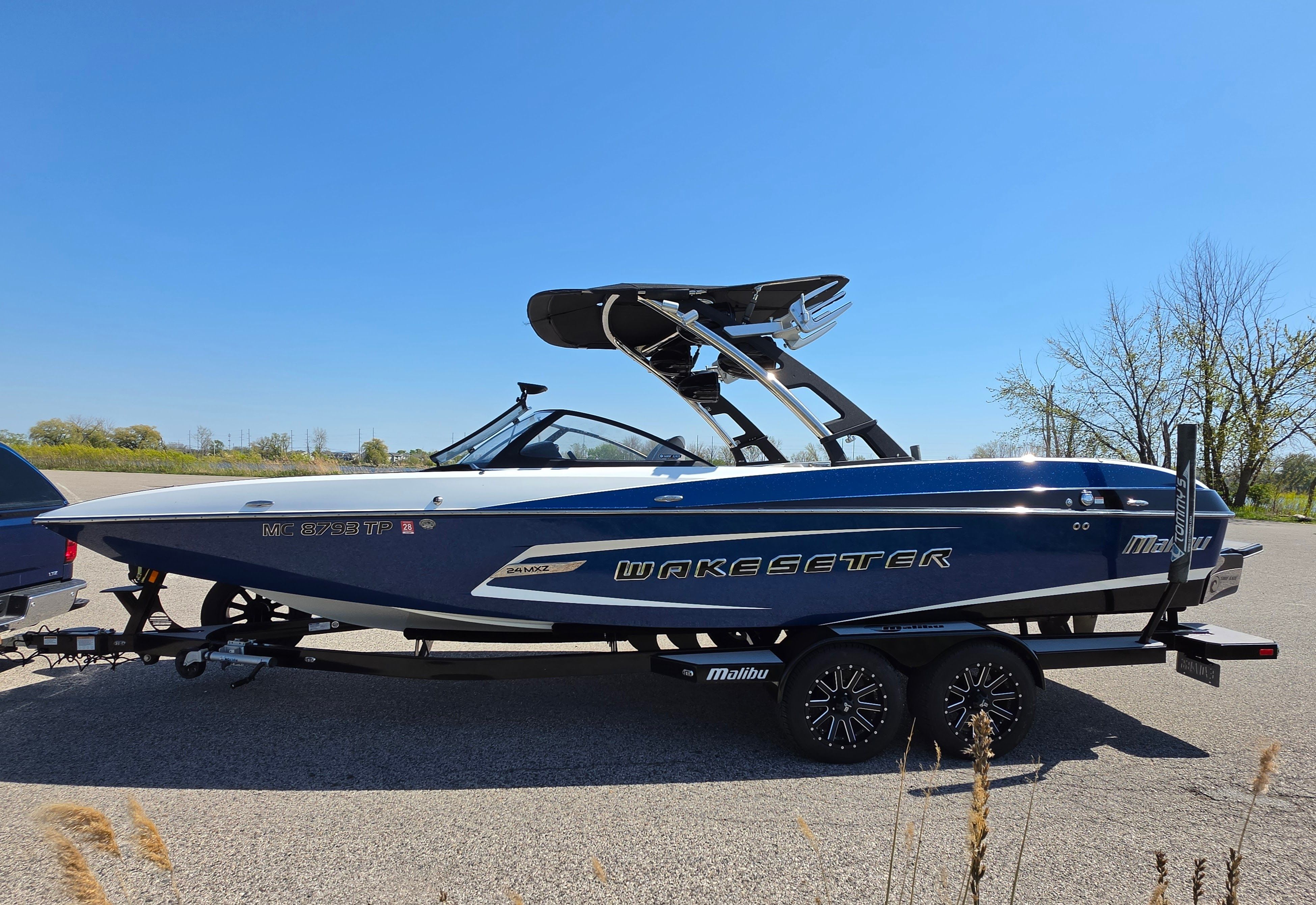 2014 Malibu Wakesetter 24 MXZ boat on trailer, blue sky.