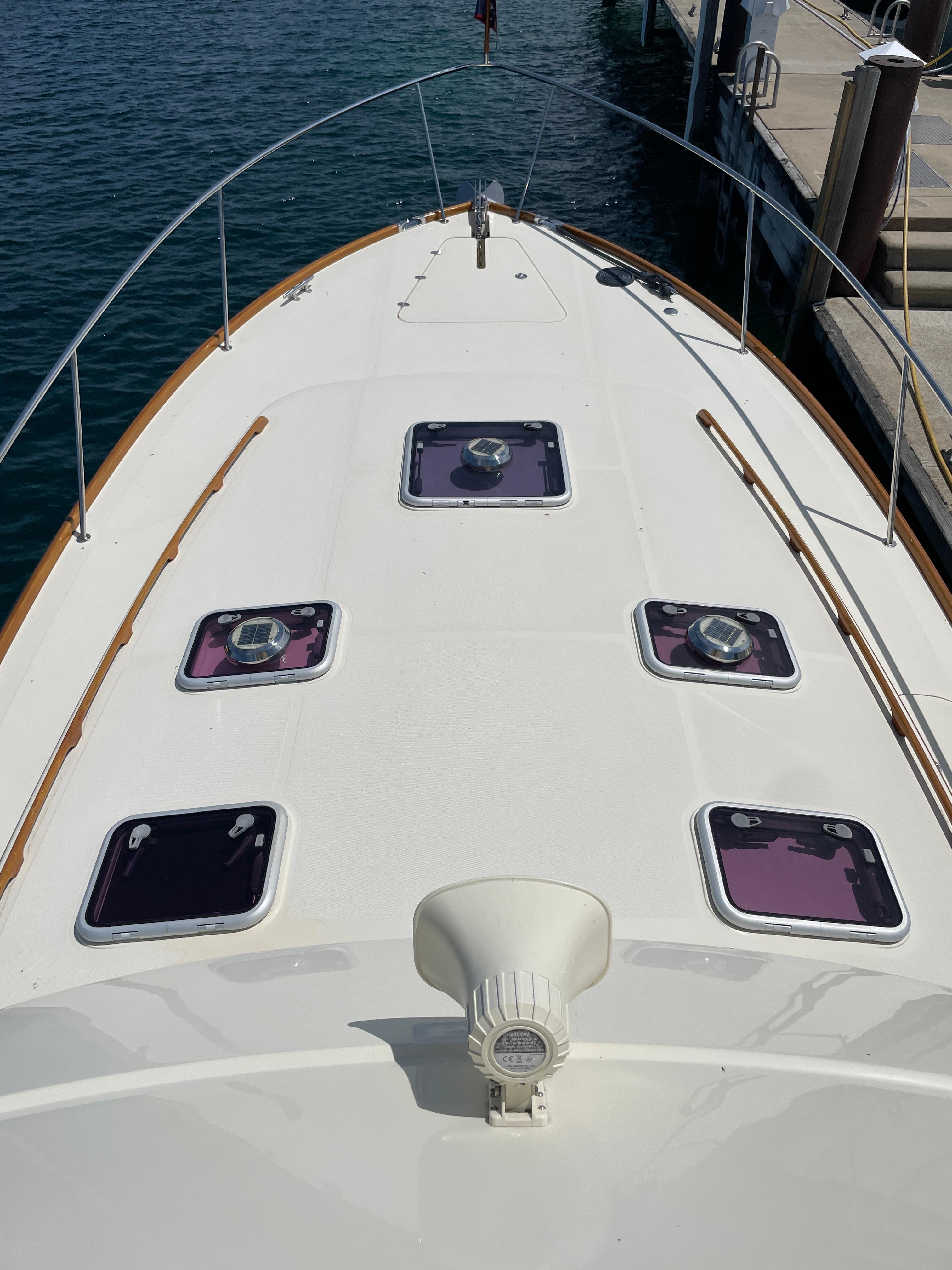 2007 Hinckley Talaria 44 Flybridge yacht deck with hatches, docked by the water.