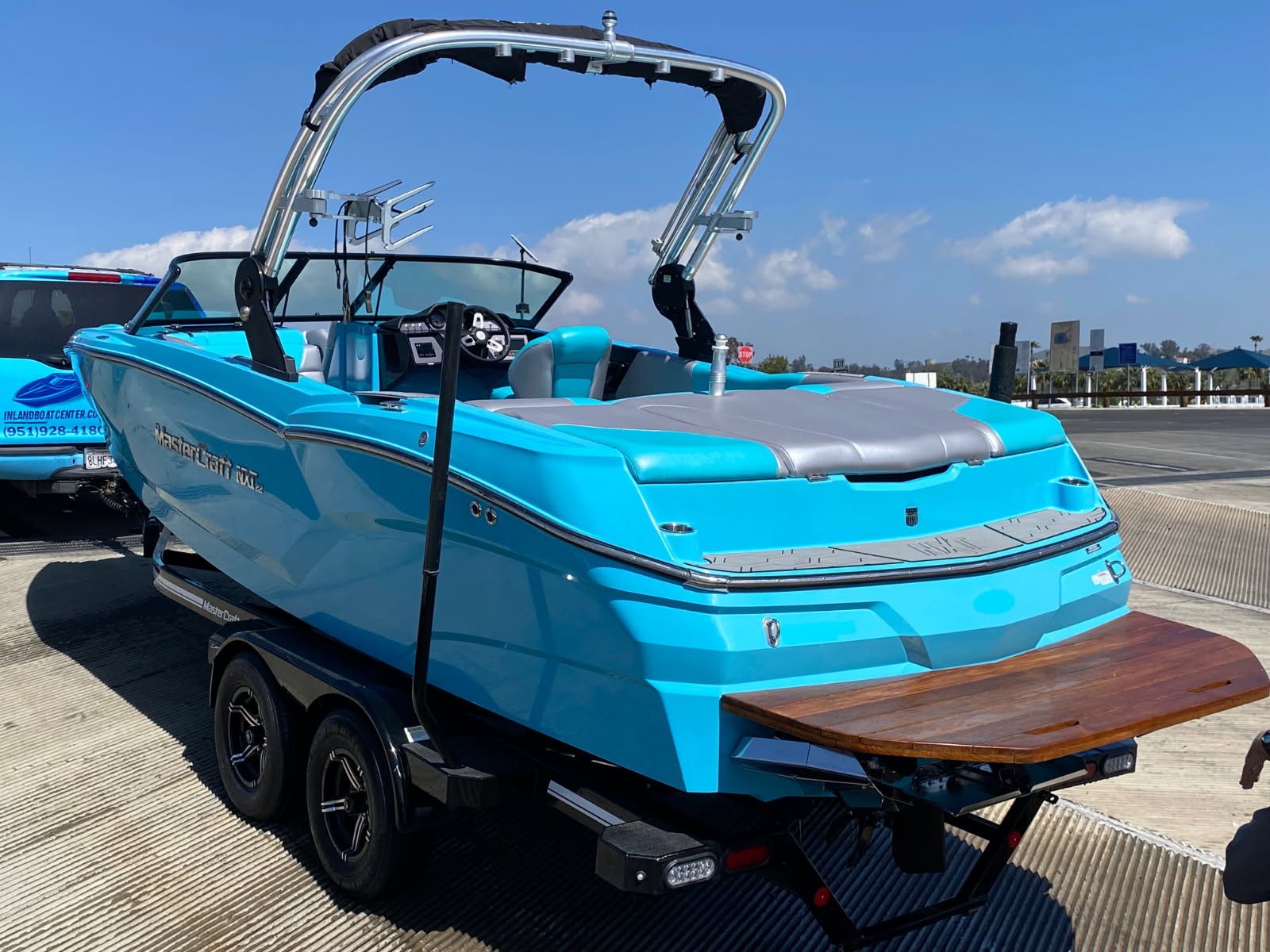 2021 MasterCraft NXT22 boat on trailer, blue, sunny day.