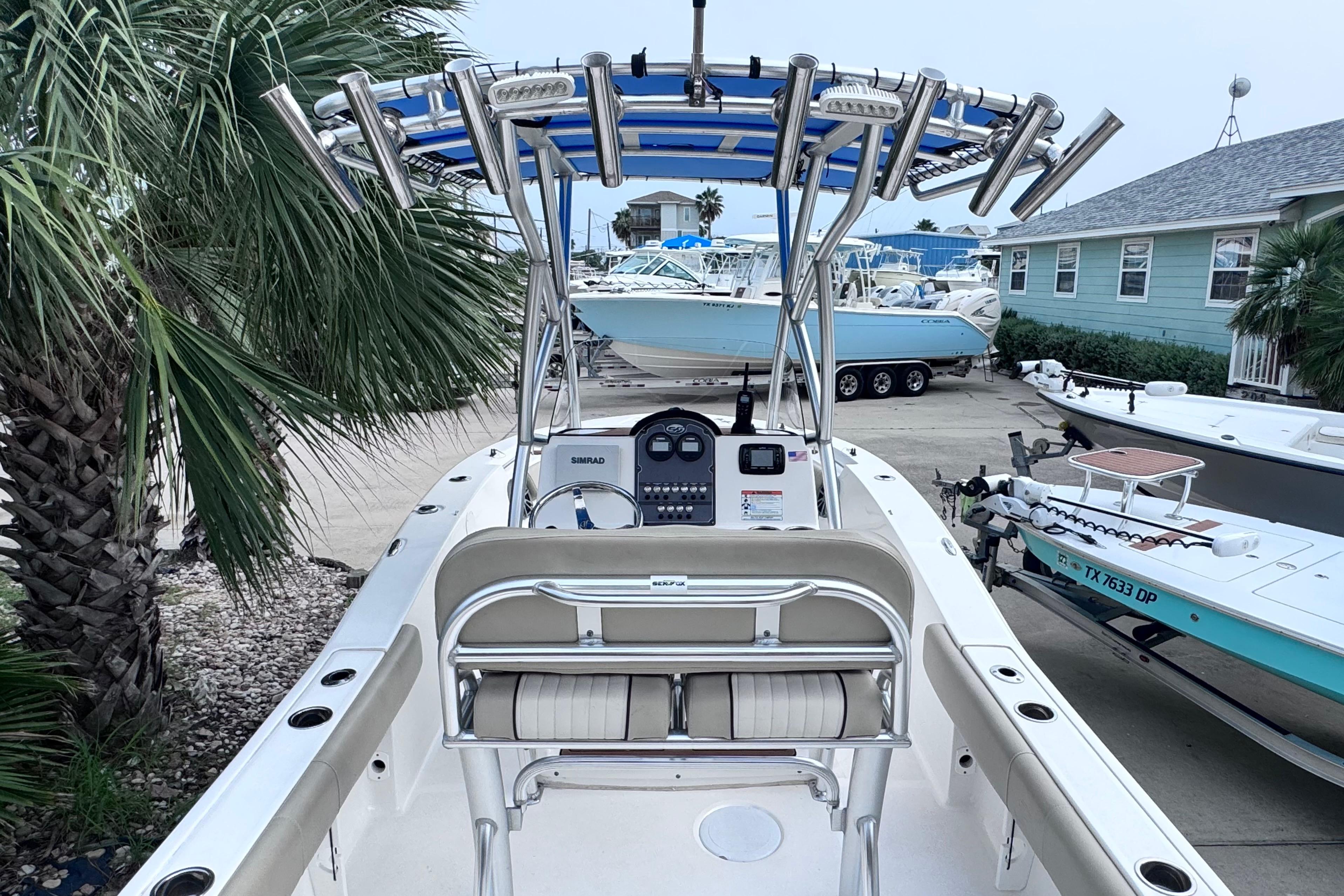 2018 Sea Fox 206 Commander boat with T-top and console, docked near palm trees.
