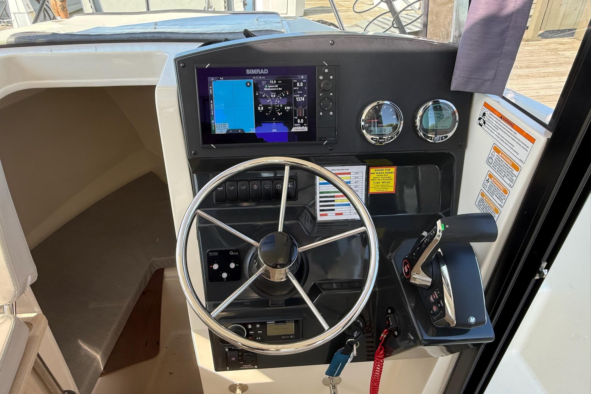 2024 Bayliner Trophy T25 Pilothouse helm with steering wheel, controls, and navigation display.