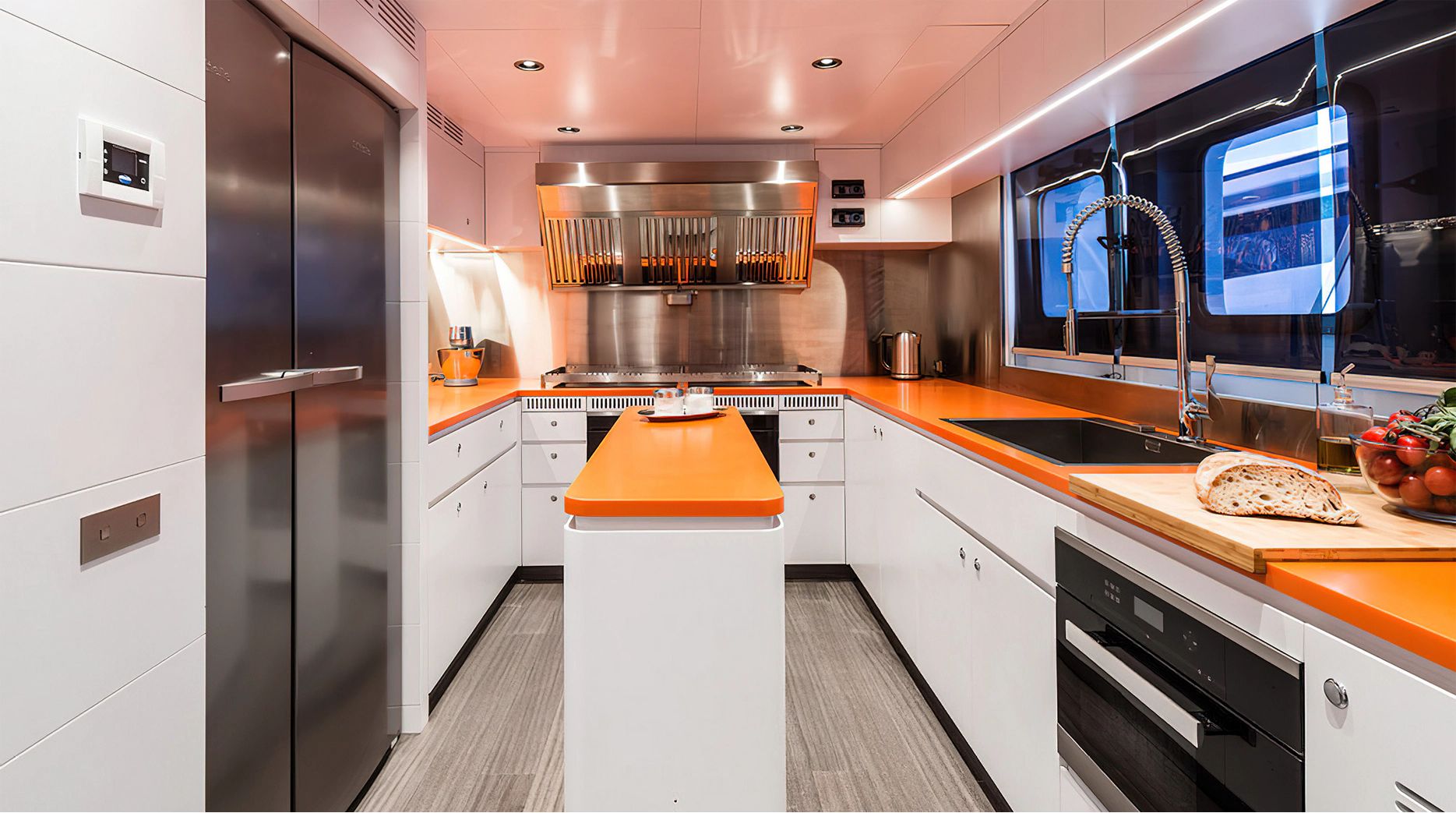 Modern yacht kitchen with orange countertops and stainless steel appliances.