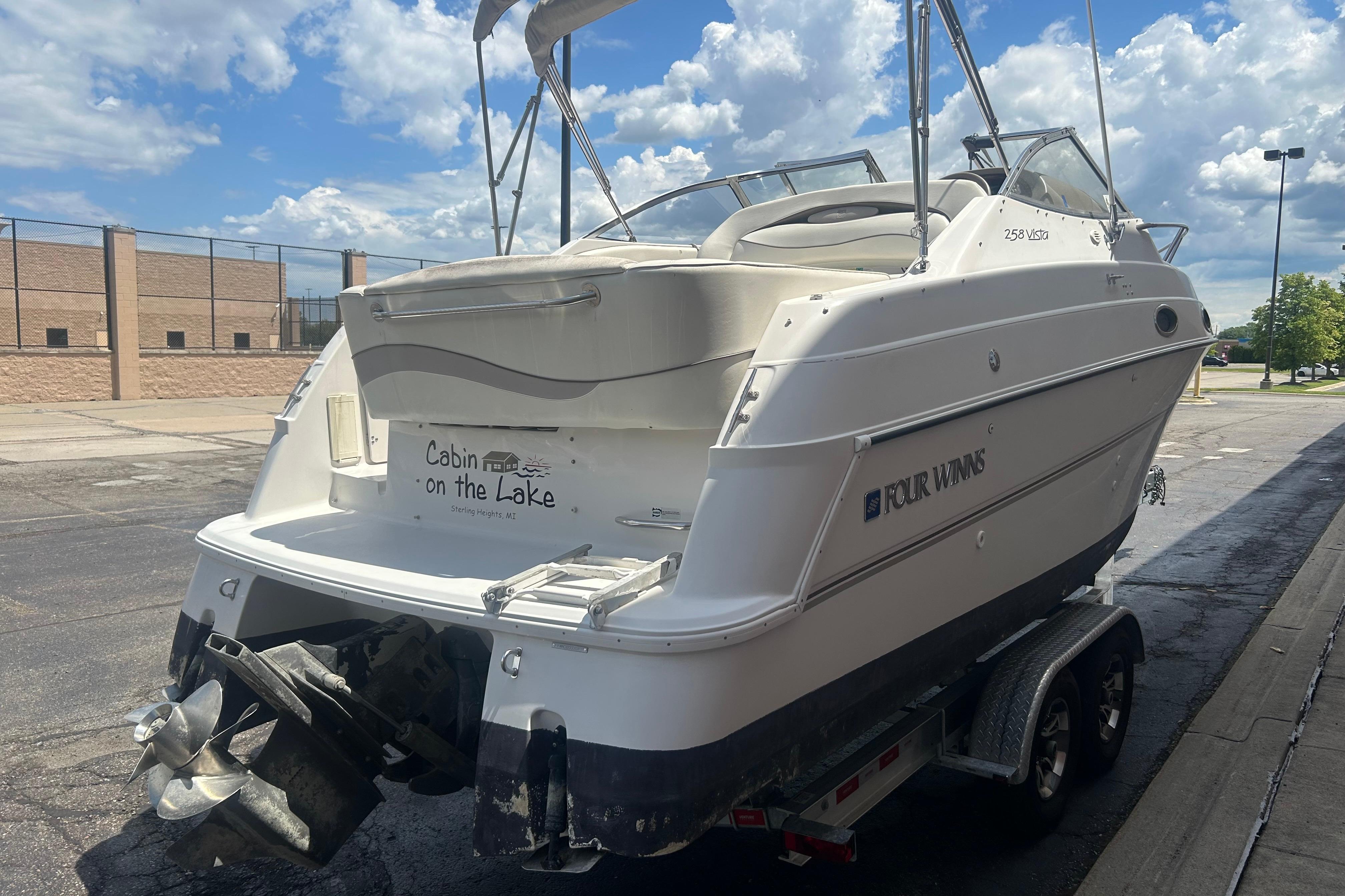 1998 Four Winns 258 Vista boat on trailer, parked outdoors under a cloudy sky.