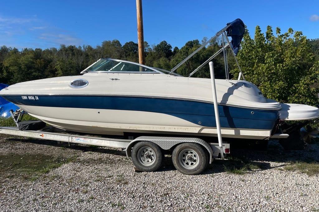 2004 Sea Ray 240 Sundeck boat on trailer, parked outdoors on gravel.