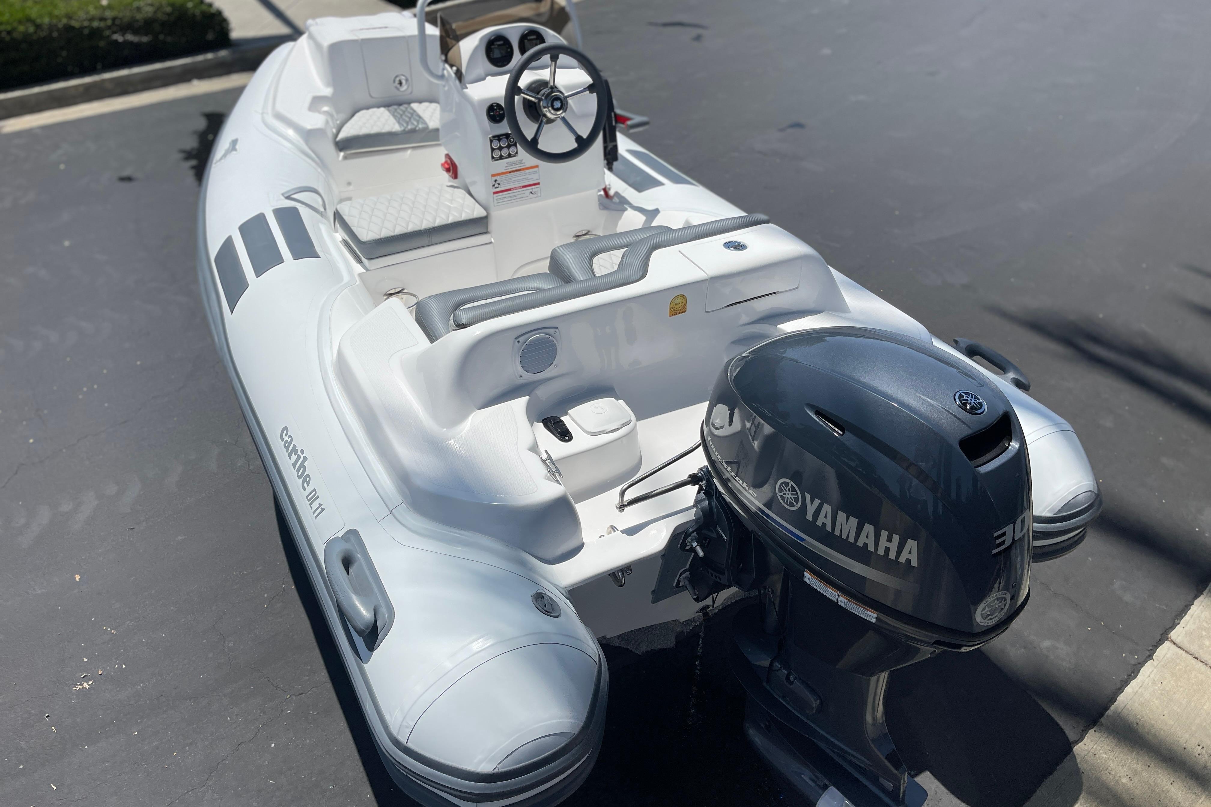 2025 Caribe DL11 inflatable boat with Yamaha outboard motor, parked on pavement.