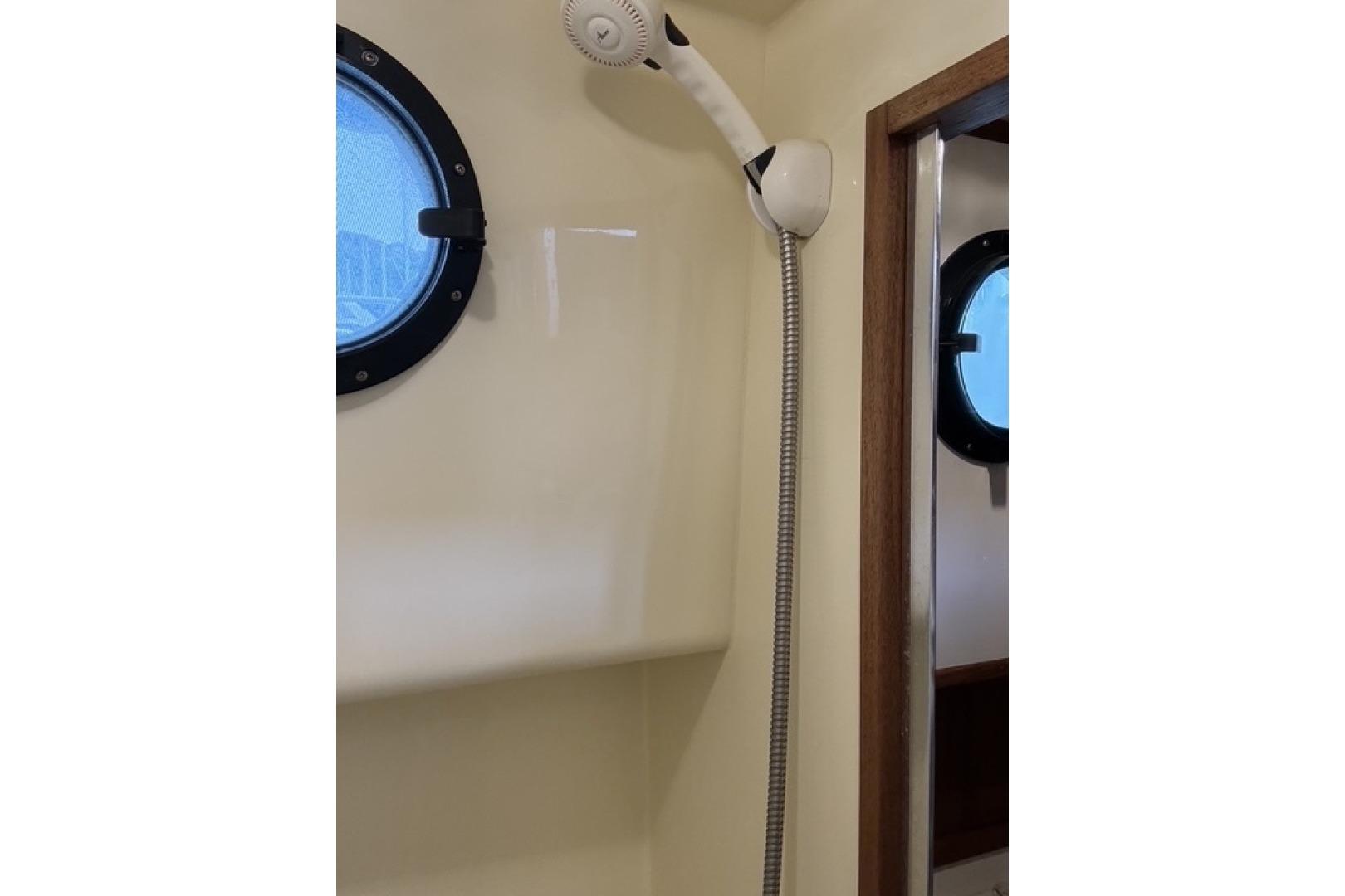 Shower area in 2000 Nordic Tug 37 boat with porthole window.