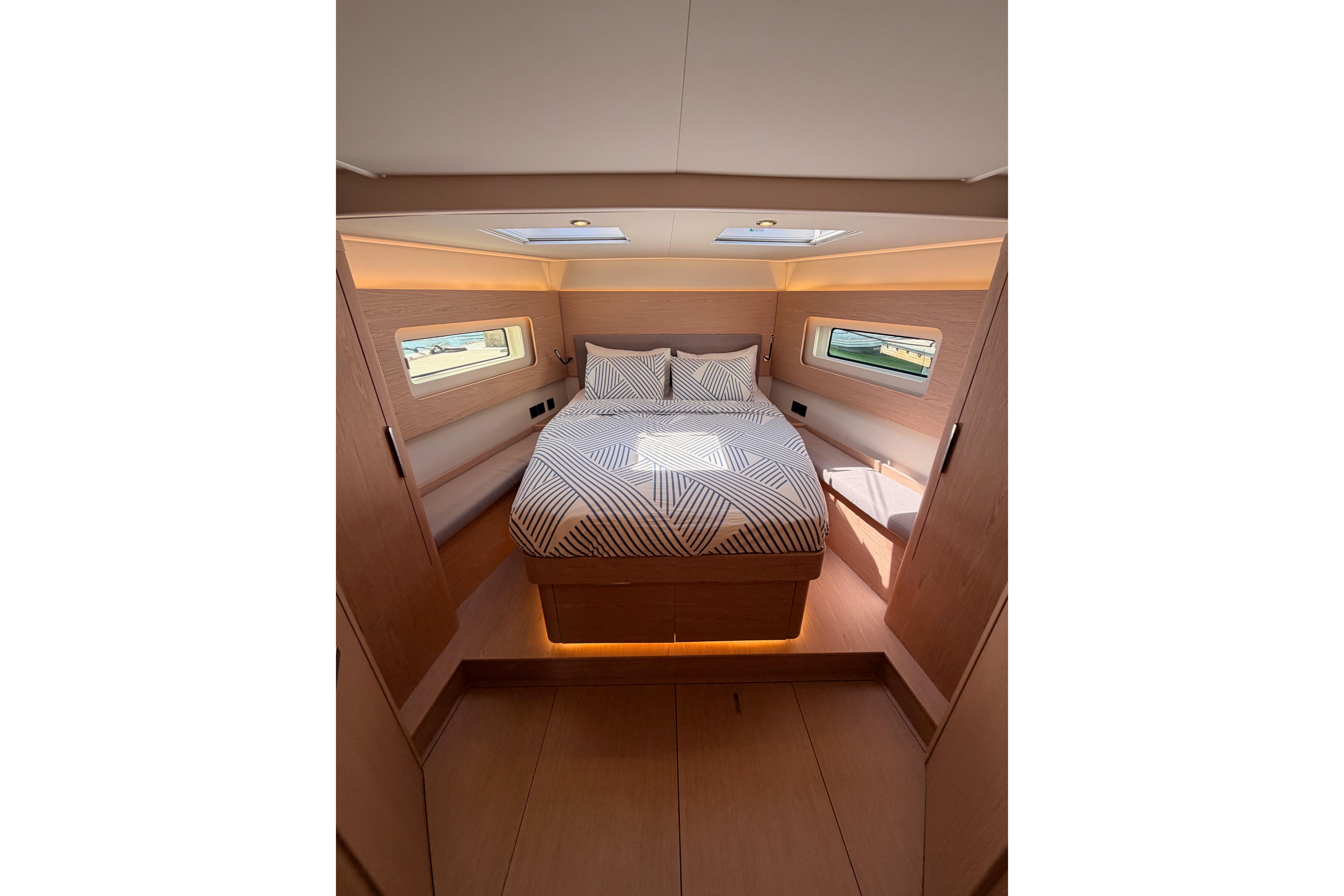 Luxurious cabin interior of 2022 Beneteau Oceanis Yacht 54 with modern design and cozy bedding.