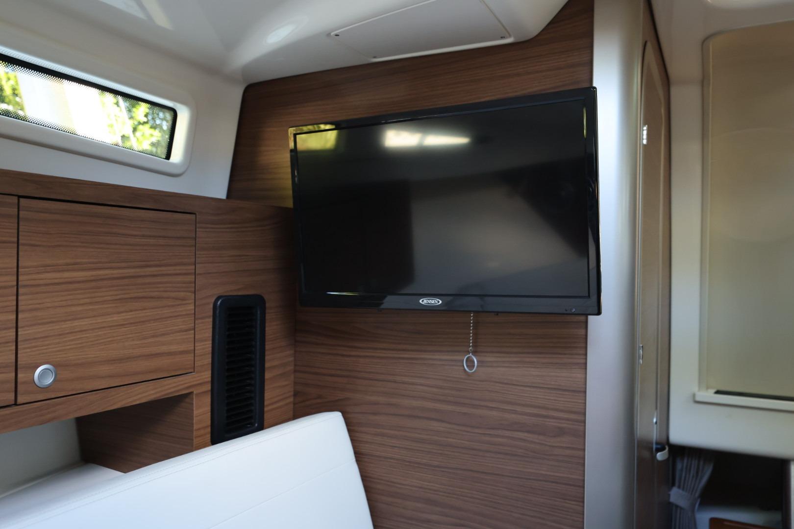 Interior of 2025 Boston Whaler 325 Conquest with mounted TV and wood paneling.