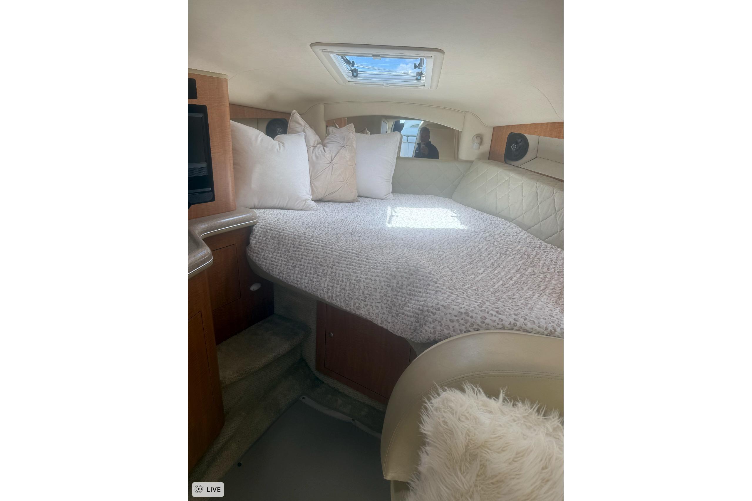 Interior cabin of 2006 Sea Ray 300 Sundancer with cozy bedding and natural light.