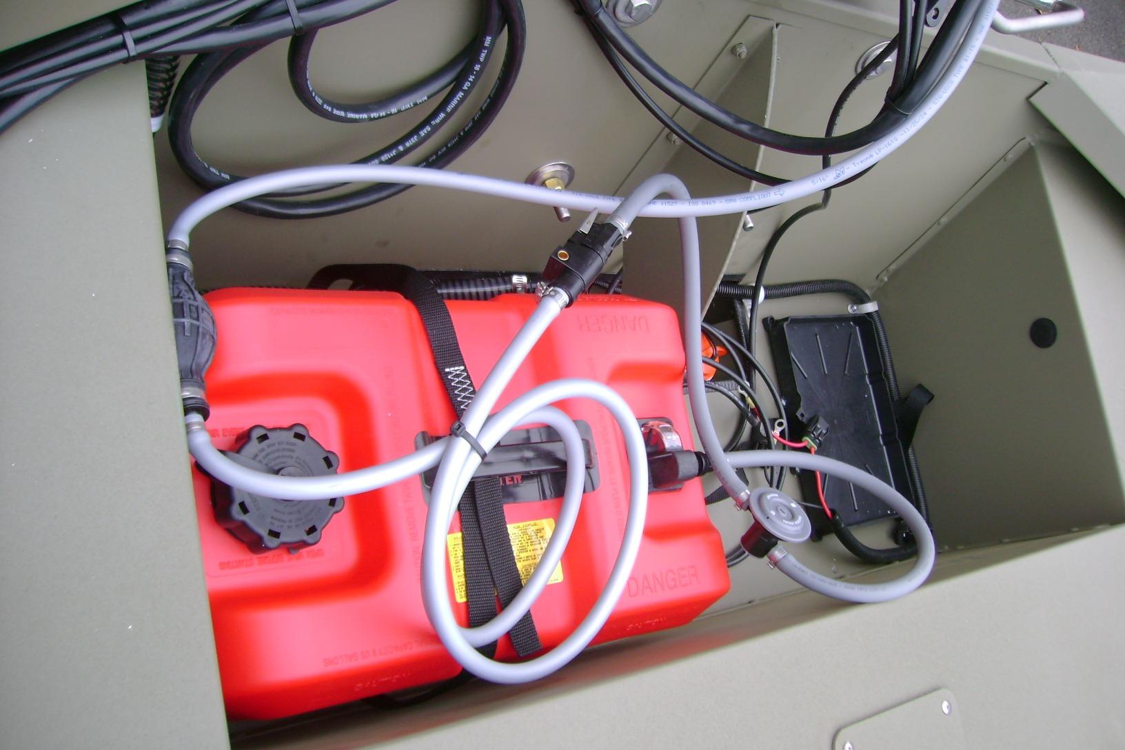 2026 Tracker Grizzly 1648 SC boat compartment with red fuel tank and wiring.