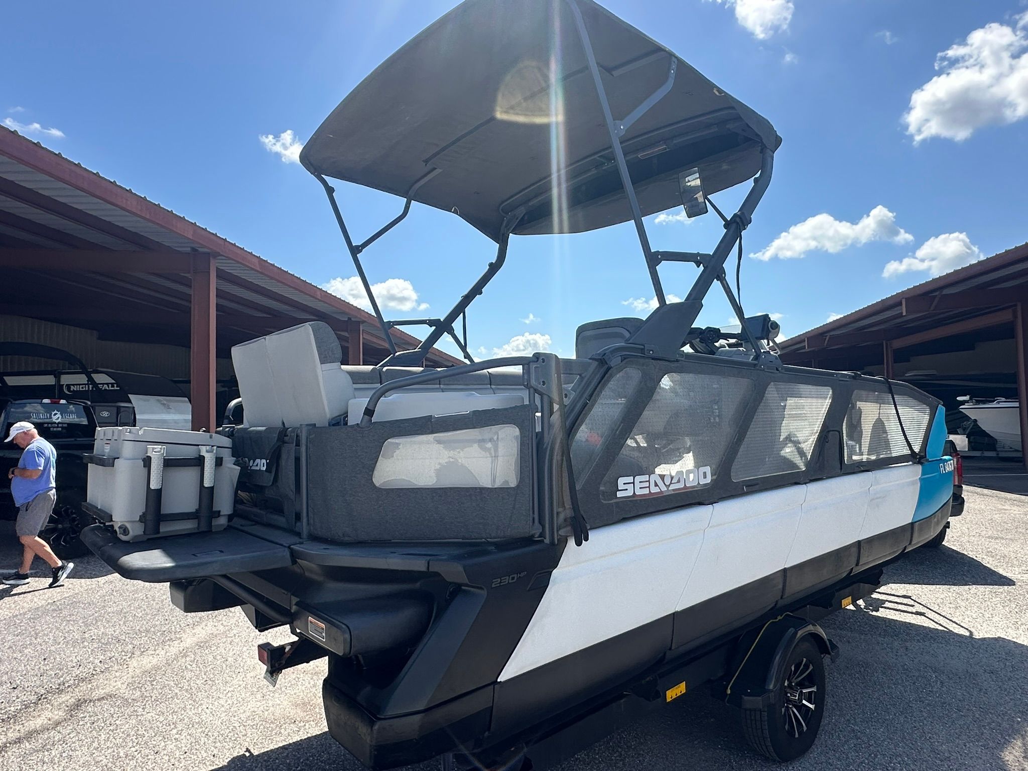A 2023 Sea-Doo 21 SWITCH SPORT with a black canopy sits on a trailer under a covered area.